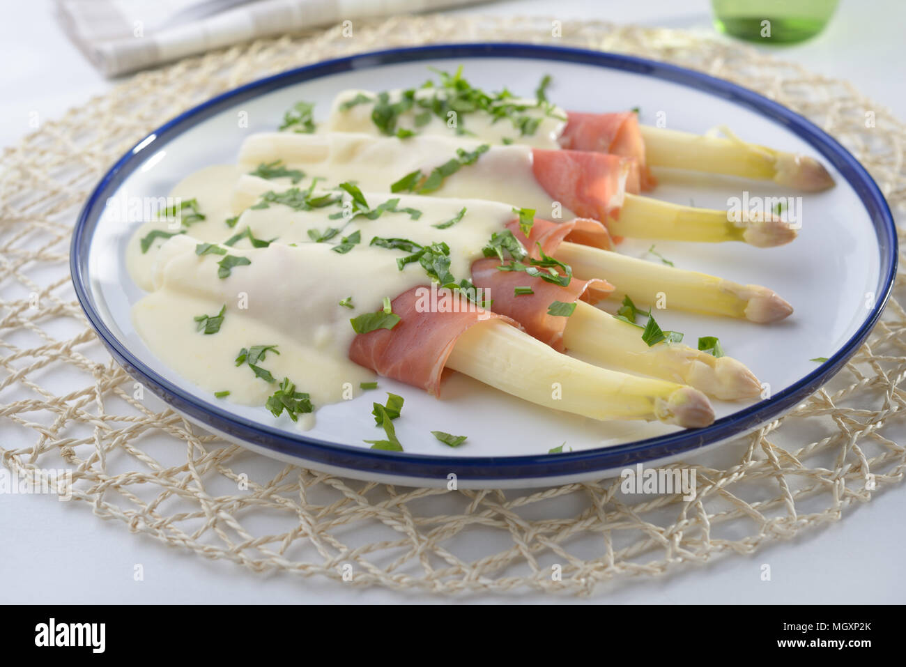 Weißer Spargel rolled-up in jamon unter Käse Sauce Stockfoto
