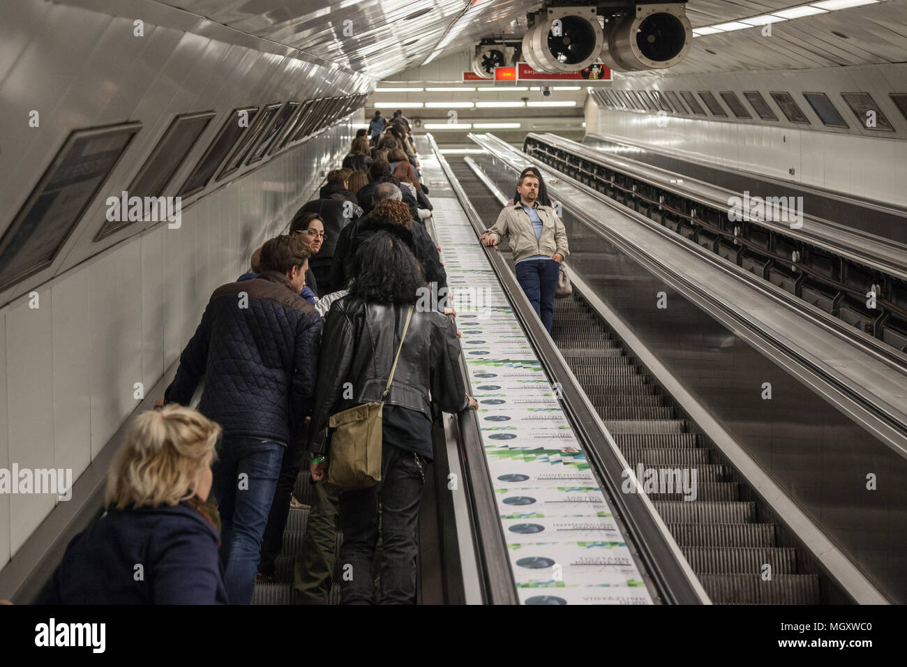 BUDAPEST, Ungarn - 7. April 2018: Die Leute von der U-Bahnstation von Budapest auf einer Rolltreppe in Stoßzeiten, leere Treppe auf das Rig gesehen werden kann. Stockfoto