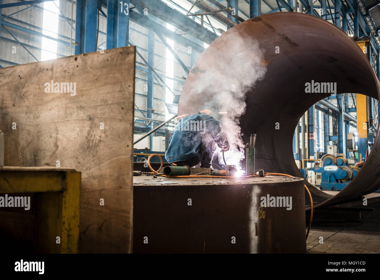 Arbeiter Schweißen im Inneren einer Fabrik Stockfoto