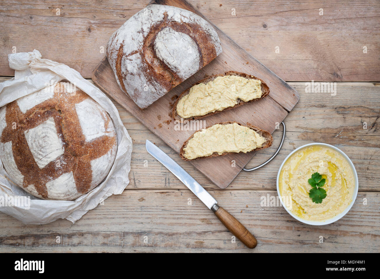 Sauerteigbrot und Dinkelsauerteig Brot mit hausgemachtem Hummus auf einem Brotbrett. VEREINIGTES KÖNIGREICH. Stockfoto