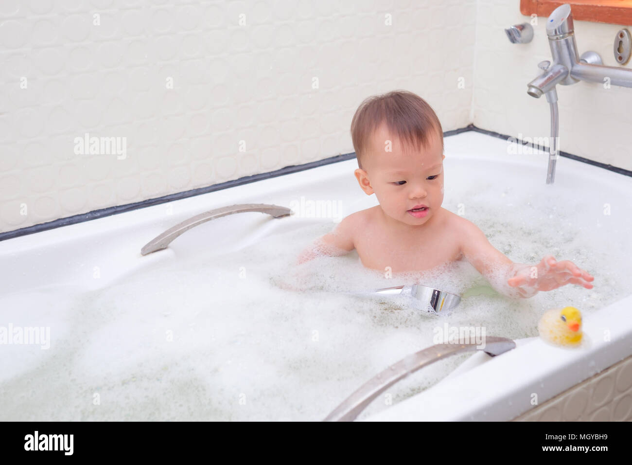 Süße kleine Asiatische 18 Monate / 1 Jahr altes Kleinkind Baby Junge Kind  Spaß sitzen in der Badewanne spielen Rubber Duck toy und eine Dusche nehmen,  indem er sich in Stockfotografie - Alamy
