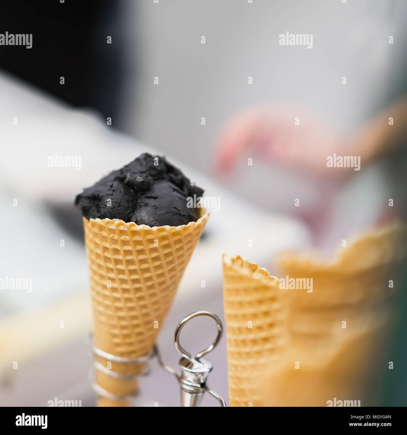 Close-up von Waffeln Kegel mit Ball von trendiges schwarzes Eis. Köstliche Kühlung teil an einem heißen Tag und nur zum Spaß. Selektive konzentrieren. Reale Szene in s Stockfoto