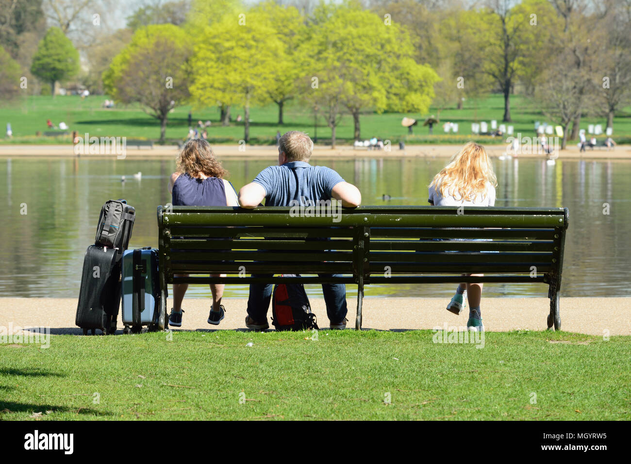 Entspannen Sie sich auf einer Bank durch die Serpentine, Hyde Park, London, Vereinigtes Königreich Stockfoto