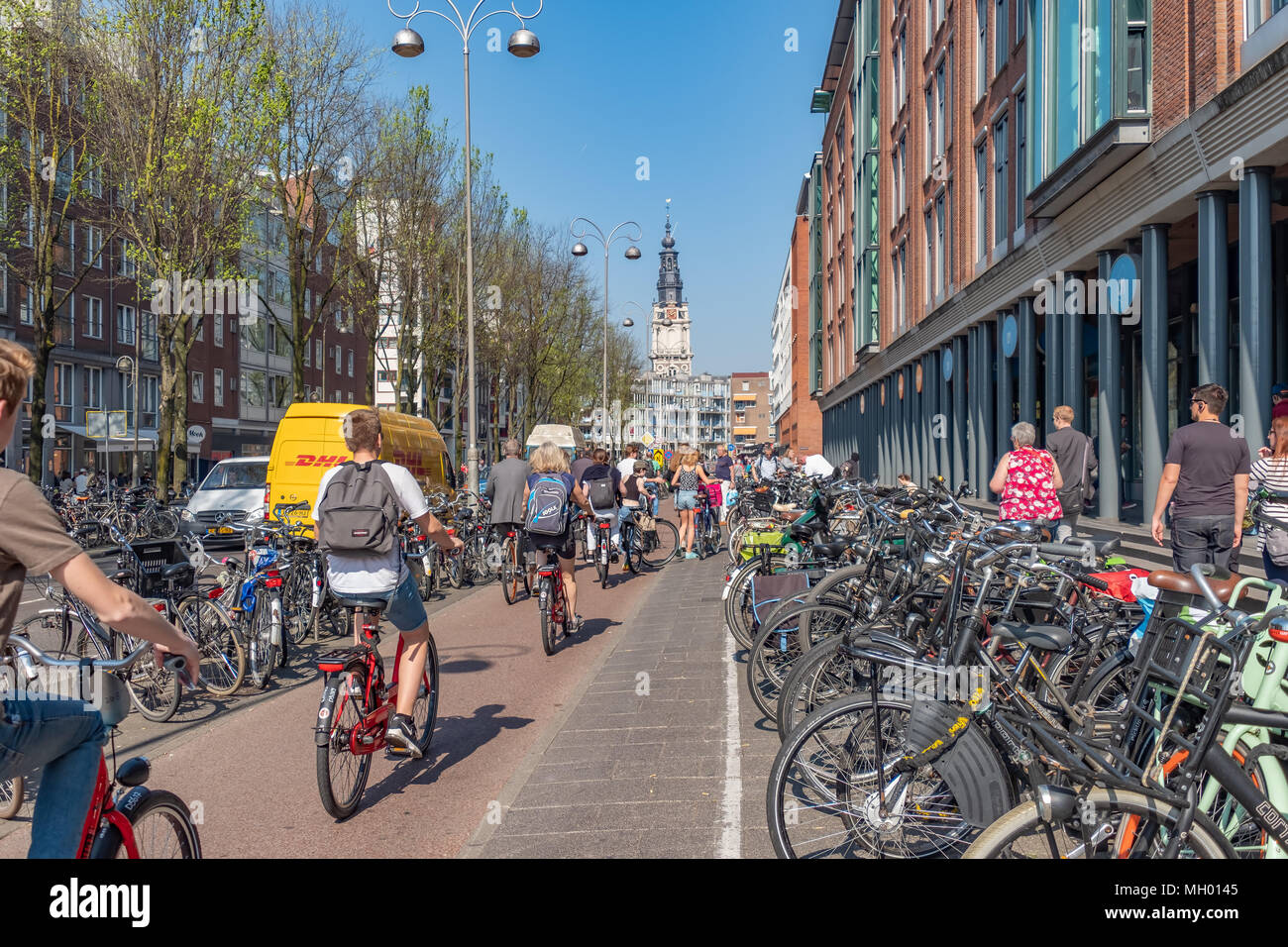 Radfahrer der Geschwindigkeit durch den Regalen halten viele Fahrräder in  Amsterdam an einem schönen Frühlingsmorgen. Es gibt mehr Fahrräder als in Amsterdam  gibt es bewohnen Stockfotografie - Alamy