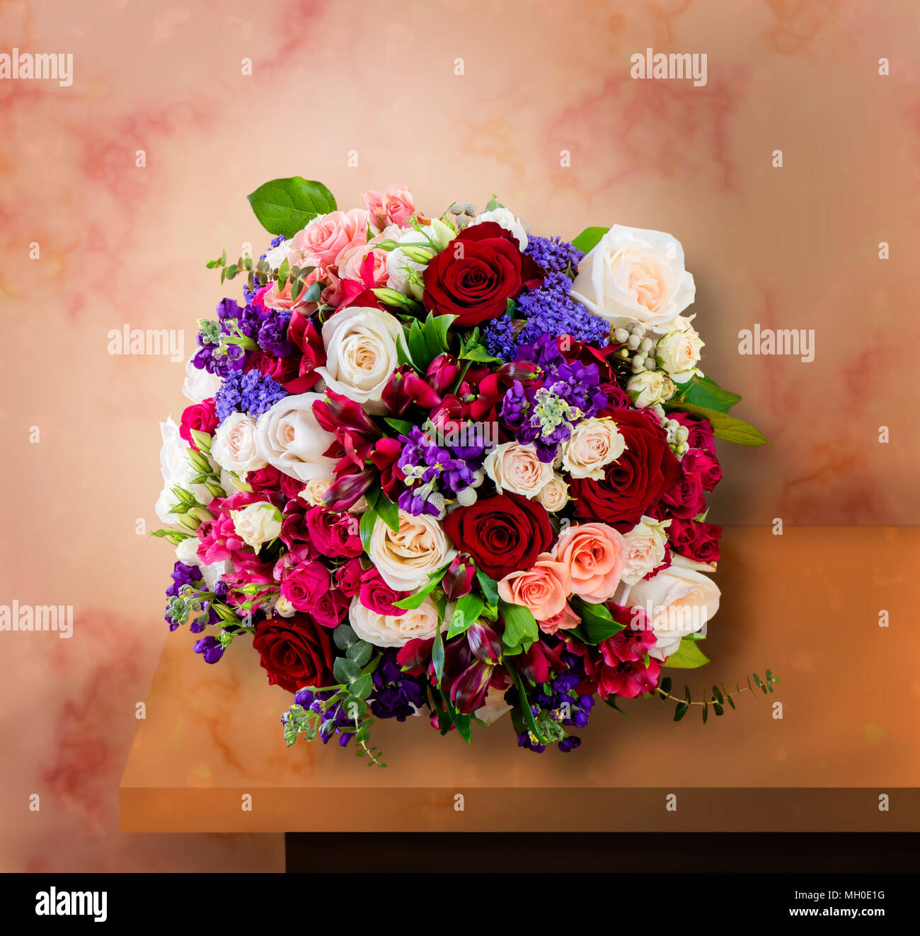 Blick von oben auf einen schönen Blumenstrauß, bunte Rosen mit grünen Blättern, stehend auf einem Marmortisch Stockfoto