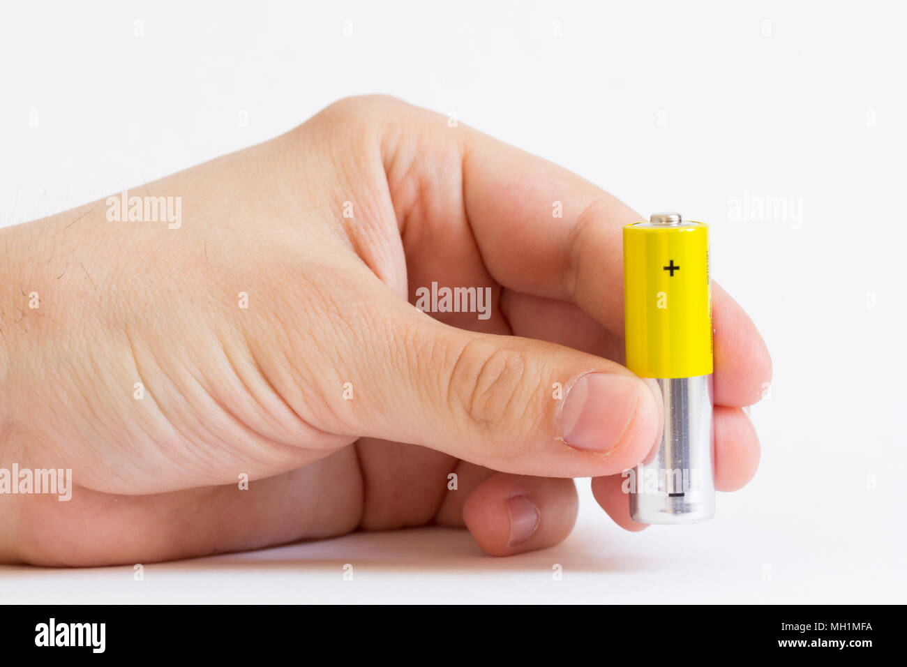 Finger Holding gelb AA-Batterie Stockfoto