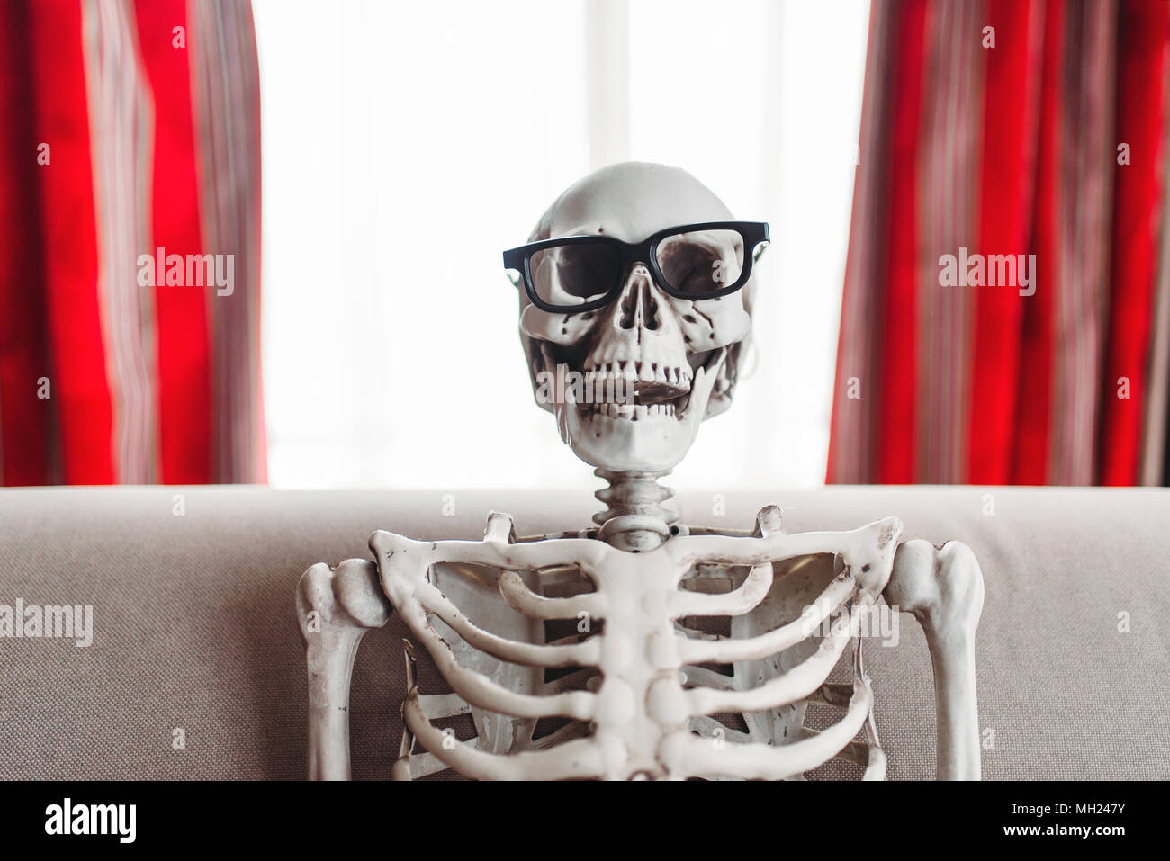 Lächelnde Skelett in Brille sitzt auf der Couch Stockfotografie - Alamy