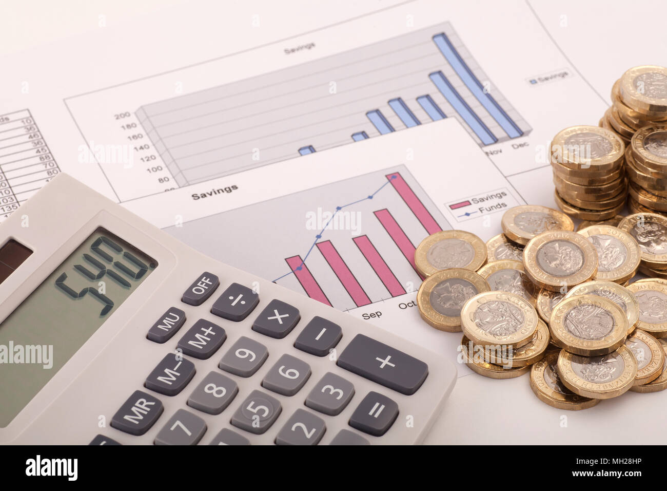 Ein Rechner sitzen auf einige Grafiken beschriftet Einsparungen und Mittel mit einigen neuen (Post 2016) Pound Münzen. Stockfoto