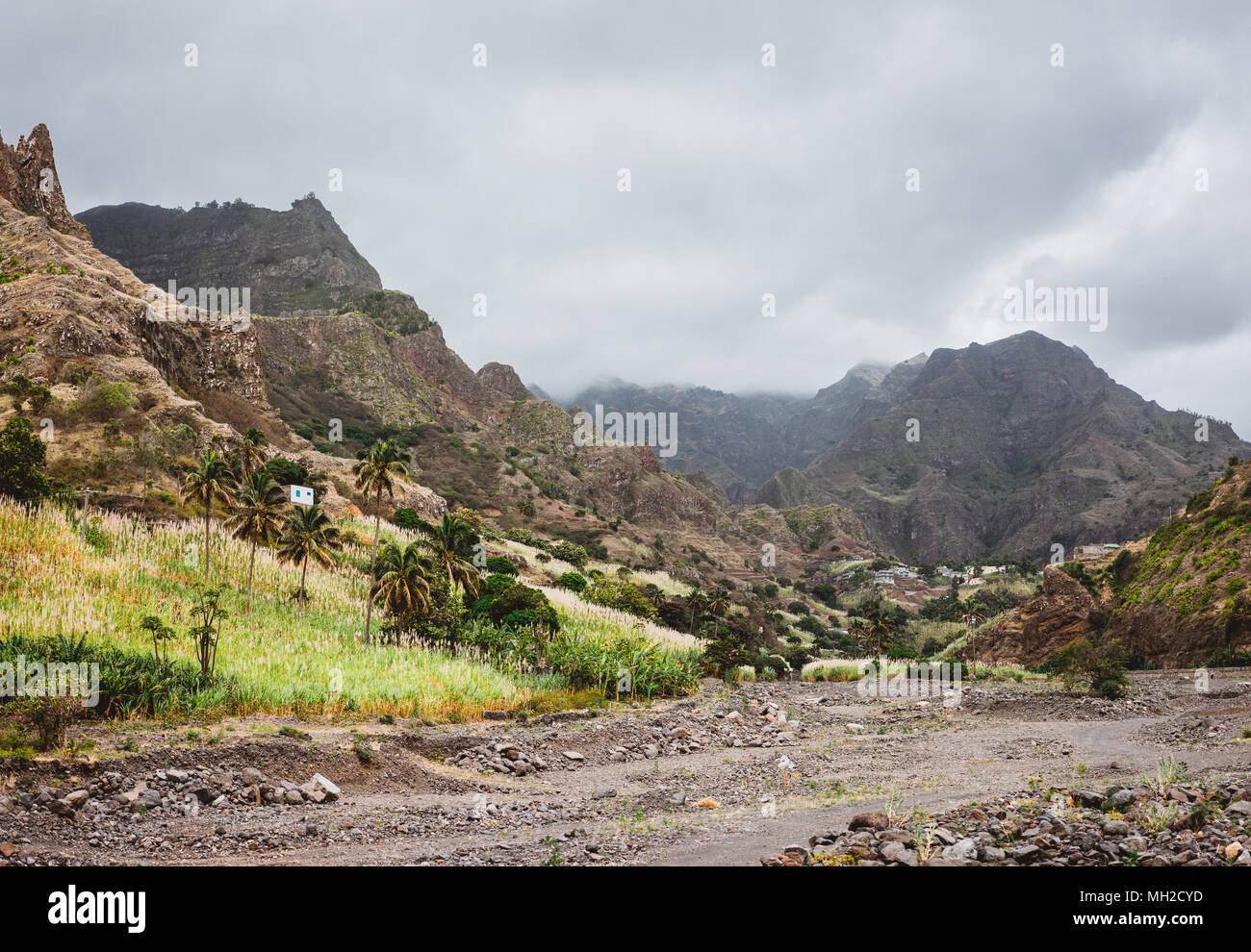 Panorama der ausgetrockneten Bach von den fruchtbaren grünen Tal und schroffen Klippen umgeben. Einsame weiße Haus auf dem Hügel. Santo Antao, Cabo Verde Stockfoto