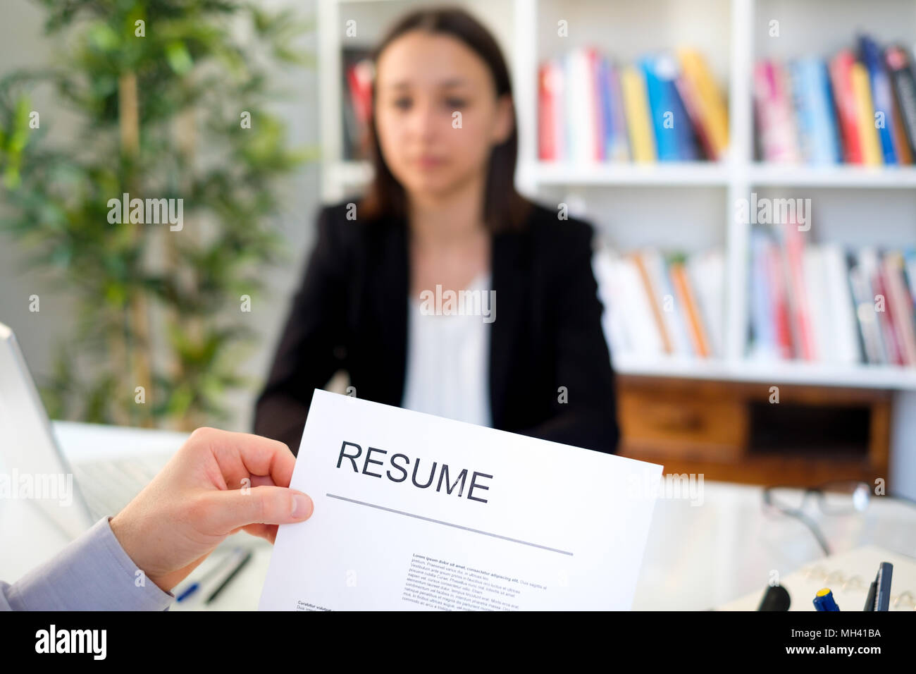 Junge Frau beim Vorstellungsgespräch, Schwerpunkt auf der CV-Resume Stockfoto