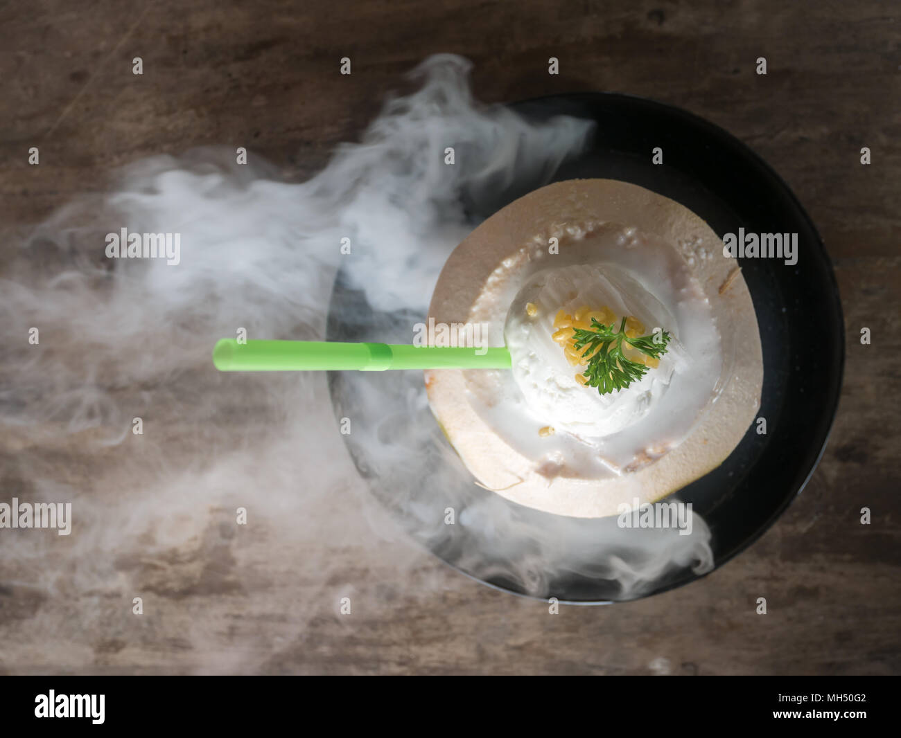 Eis Kokosnuss im Coconut Obst mit Rauch auf Holz Tisch. Ansicht von oben. Stockfoto