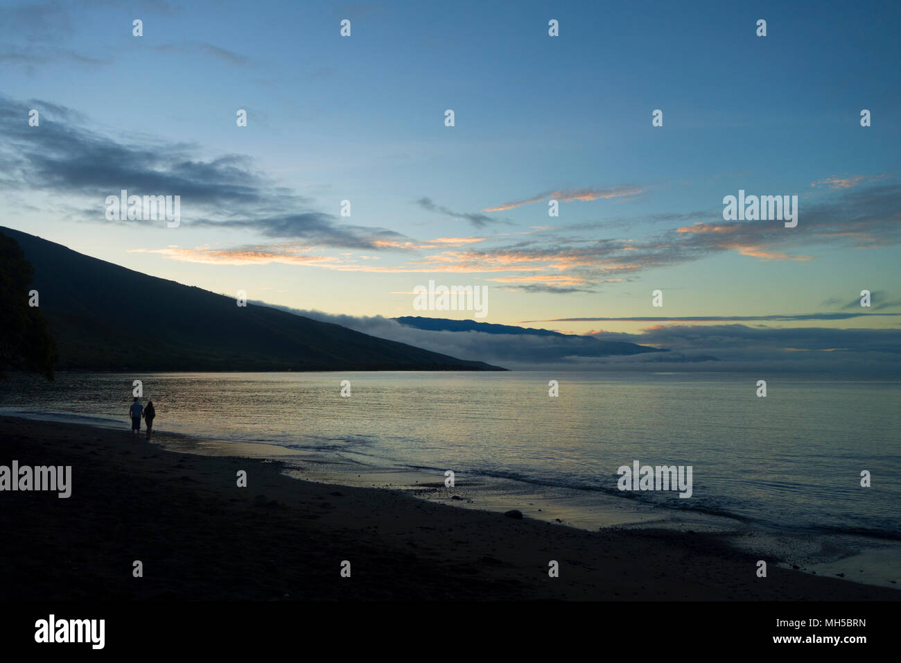 Schöne Blau Gelb Rot Himmel bei Dämmerung mit ein Paar zu Fuß der Küste mit Blick auf die Berge Stockfoto Schöne Blau Gelb Rot Himmel bei Dämmerung mit ein Paar zu Fuß der Küste mit Blick auf die Berge Stockfoto