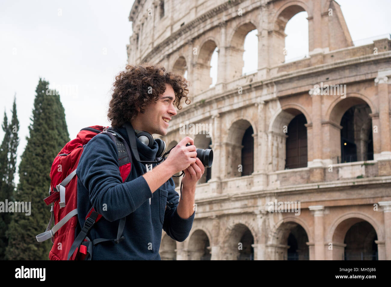 Hübscher junger Tourist Mann mit Kamera und Rucksack, die Bilder von Kolosseum in Rom, Italien. Jungen Touristen, die Bilder von Kolosseum Stockfoto