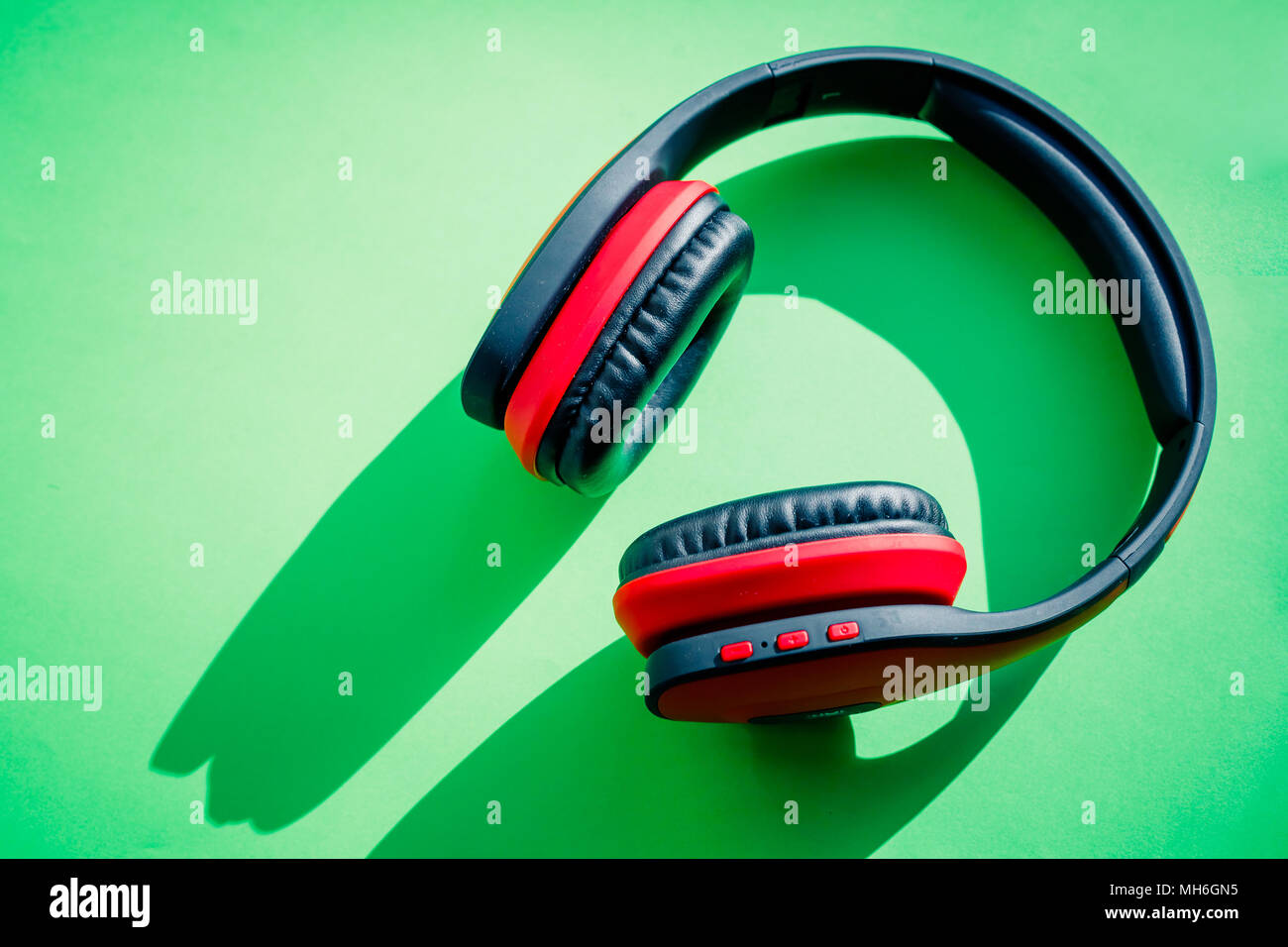 Moderne schwarze und rote kabellose Kopfhörer auf grünem Hintergrund. Das Konzept der Musik und Mode. Flachbild minimal Style. Design und Farben. Platz kopieren Stockfoto
