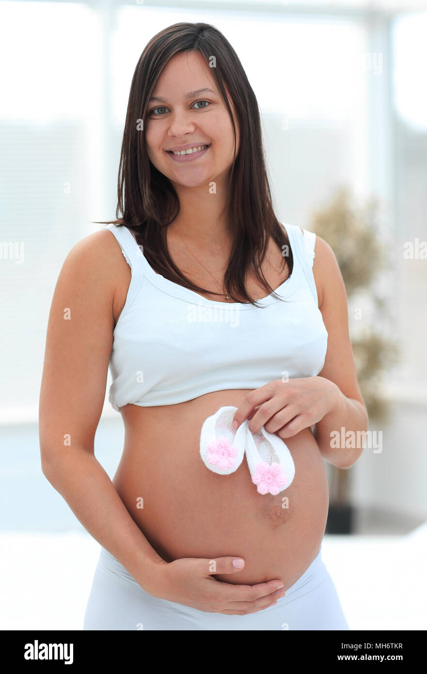 Schwangere Frau mit Baby Schuhe. in der Nähe von ihrem Abdomen. Stockfoto