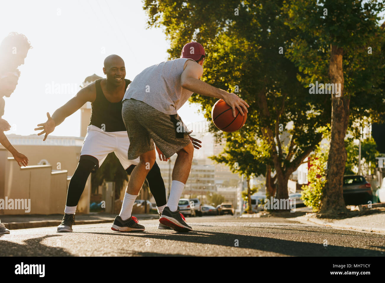 Männer spielen Basketball Spiel an einem sonnigen Tag auf einer leeren Straße. Vier Männer Basketball spielen auf der Straße. Stockfoto