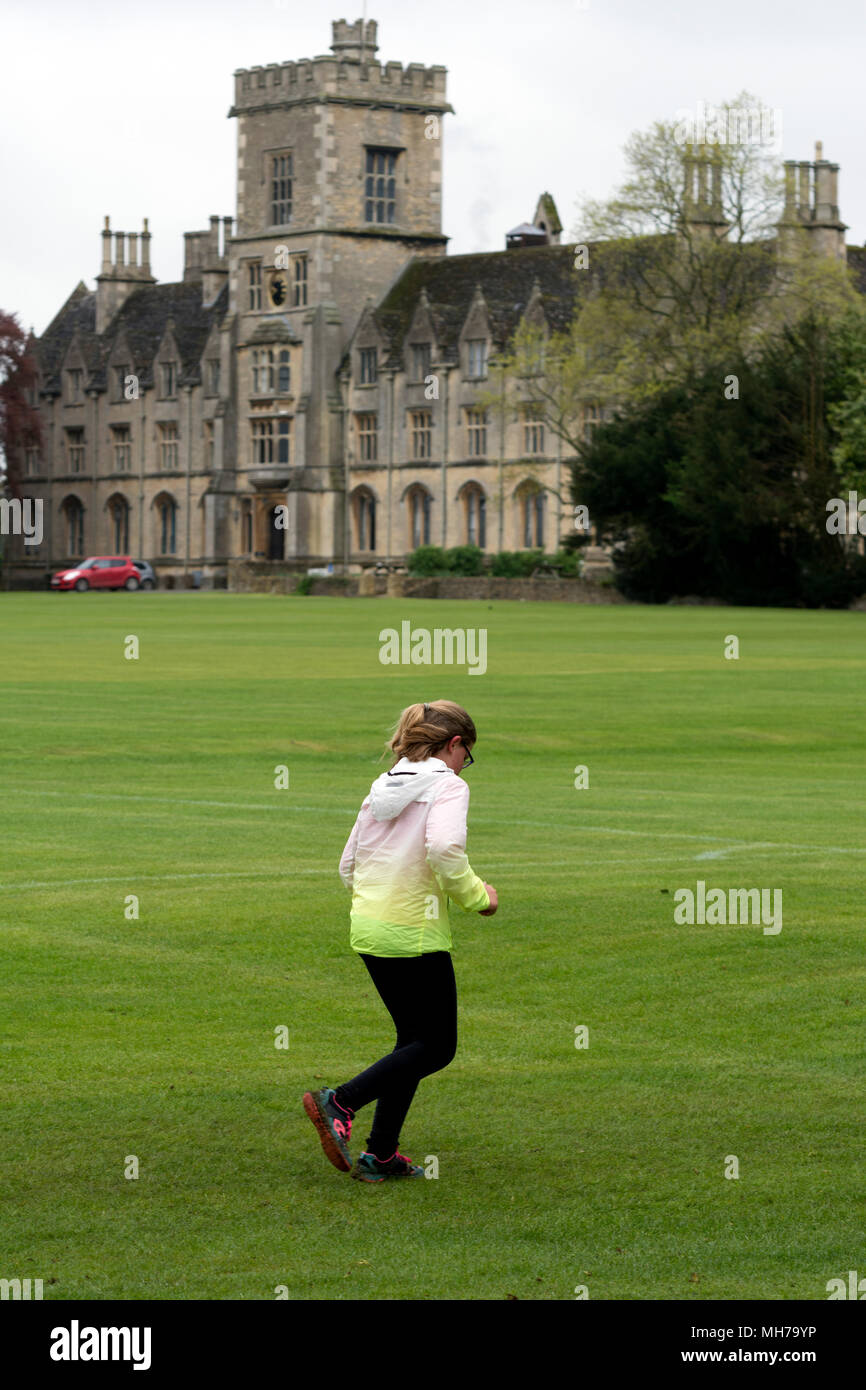 Ein Läufer in Cirencester parkrun mit der Königlichen Universität für Landwirtschaft in der Ferne, Gloucestershire, VEREINIGTES KÖNIGREICH Stockfoto