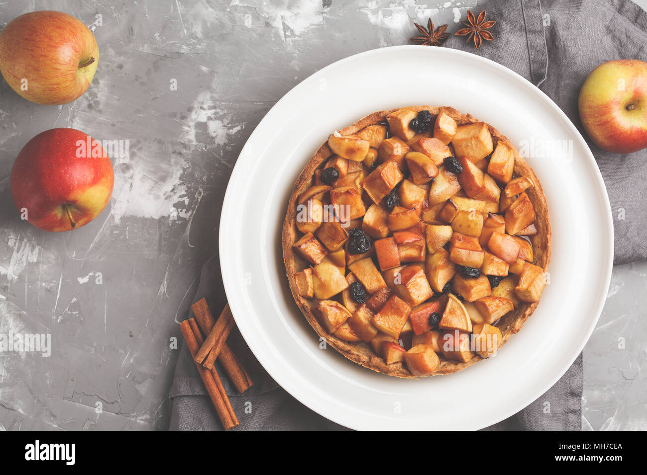 Ganze vegan Apfelkuchen mit Zimt, Rosinen und Karamell, grauen Hintergrund, Ansicht von oben Stockfoto