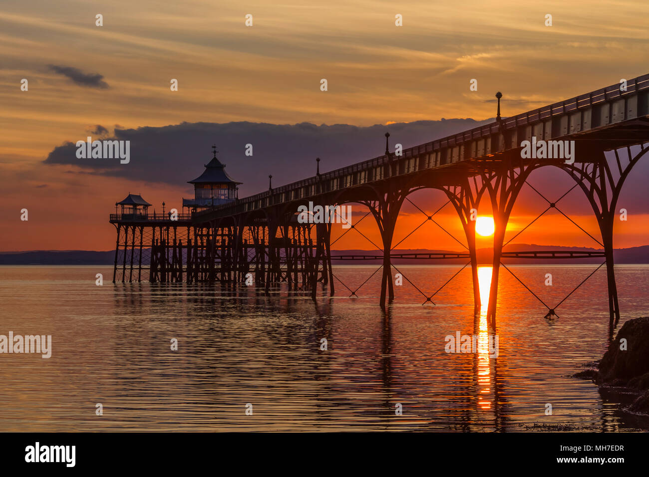 Clevedon Pier bei Sonnenuntergang mit einem Streifen von Sonnenlicht gehen über den Kanal. Stockfoto