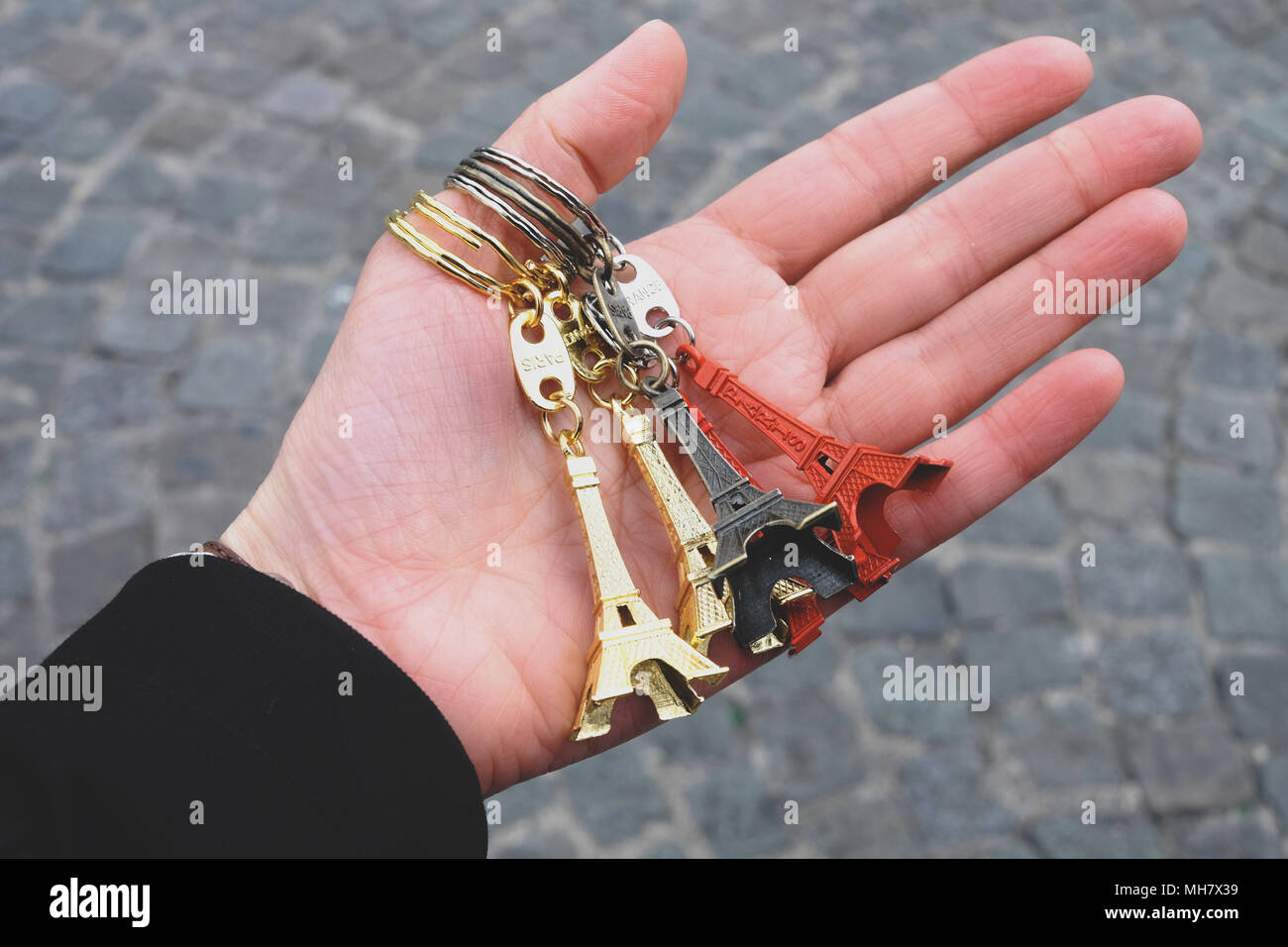 Hand, die kleine Eiffel Towers vor der Bürgersteig Stockfoto