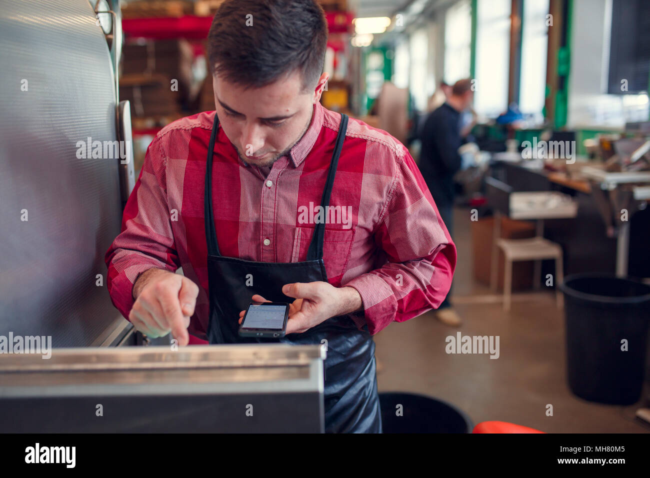 Bild der Mann mit dem Telefon am Computer von industriellen Maschinen Stockfoto
