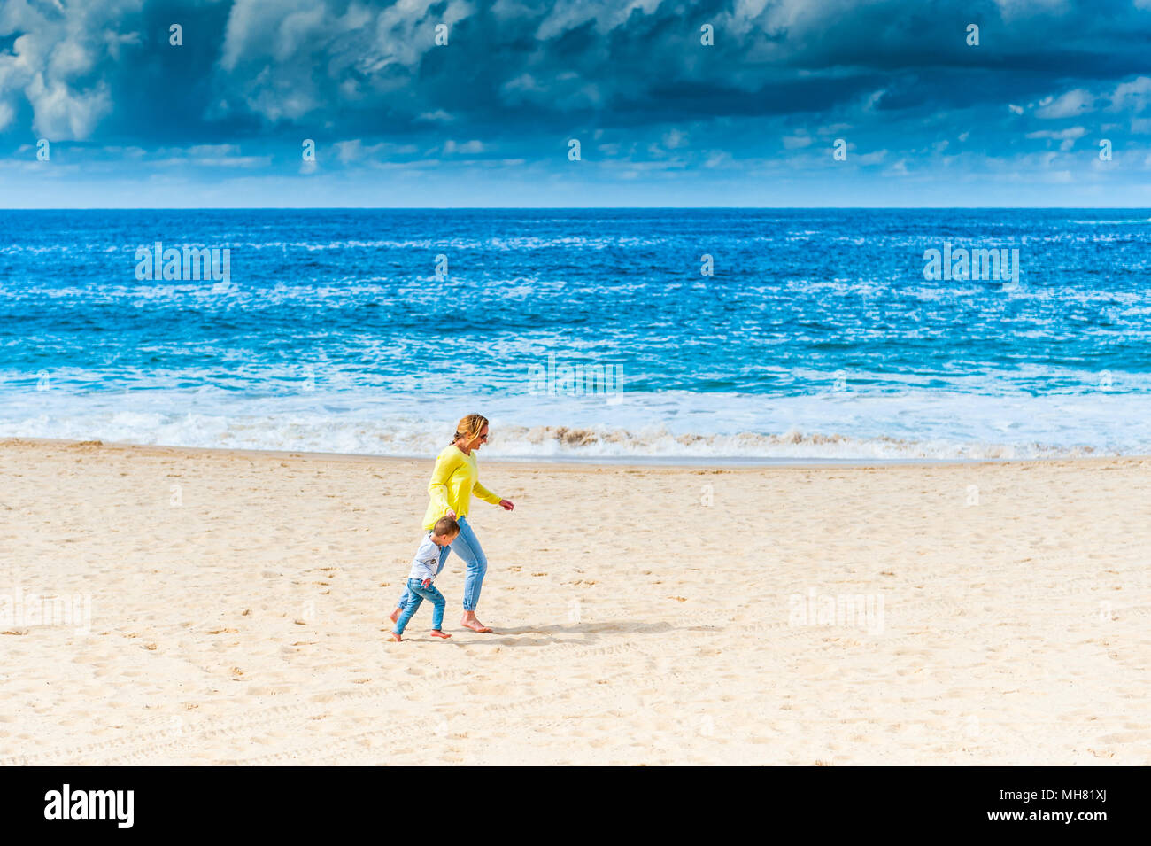 Eine Mutter geht mit ihrem Sohn über Bondi Beach, Sydney Australien mit einem Sturm über den Ozean. Stockfoto