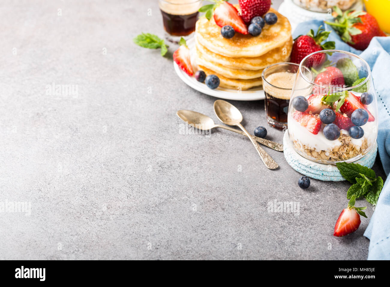 Haferflocken Müsli mit Beeren und Joghurt und panccakes auf Hellgrau konkreten Hintergrund. Gesundes Frühstück essen Konzept mit kopieren. Stockfoto