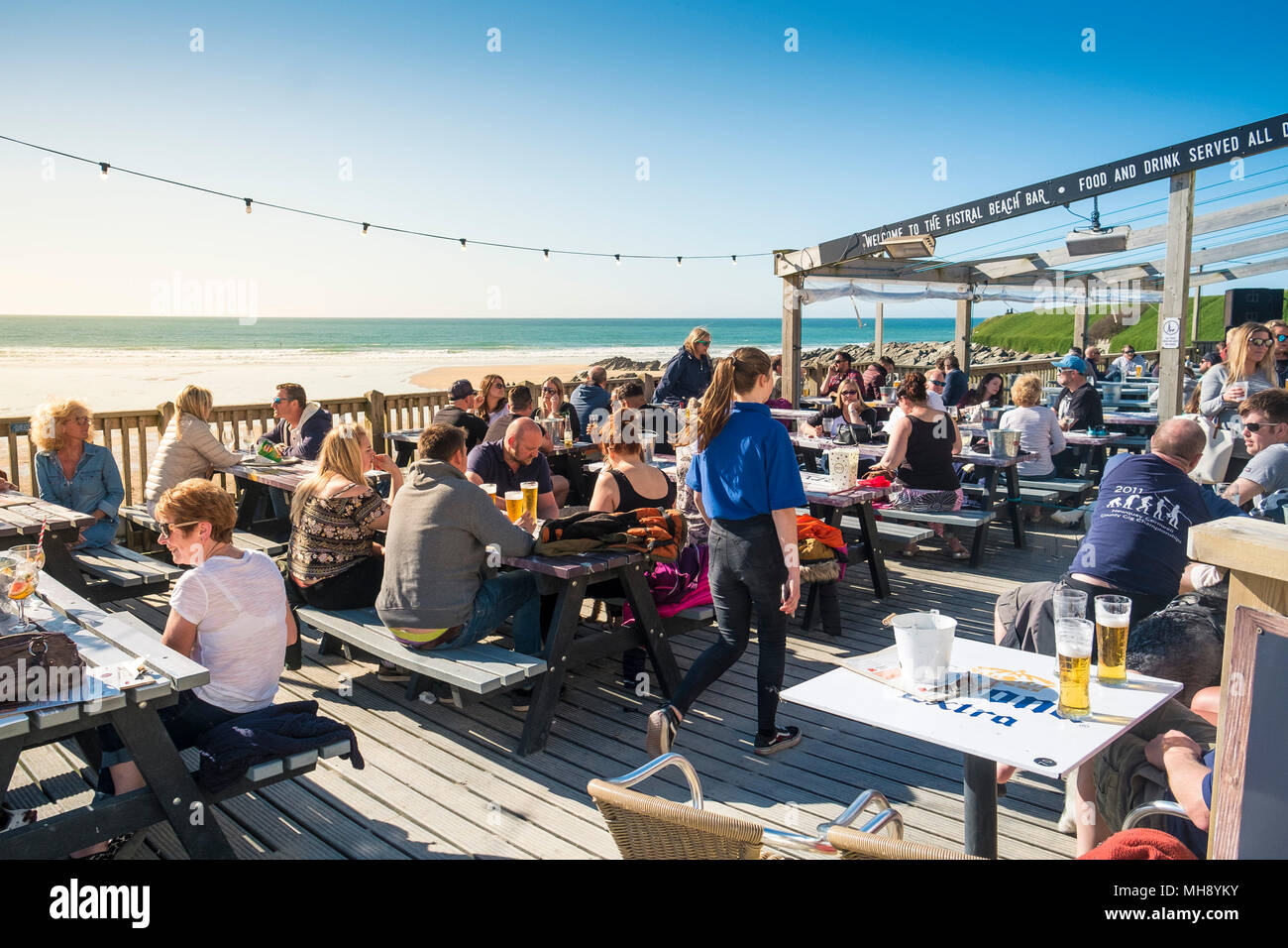 Urlauber, die sich während ihres Aufenthalts auf der Terrasse der Fistral Beach Bar entspannen und die Abendsonne genießen. Stockfoto