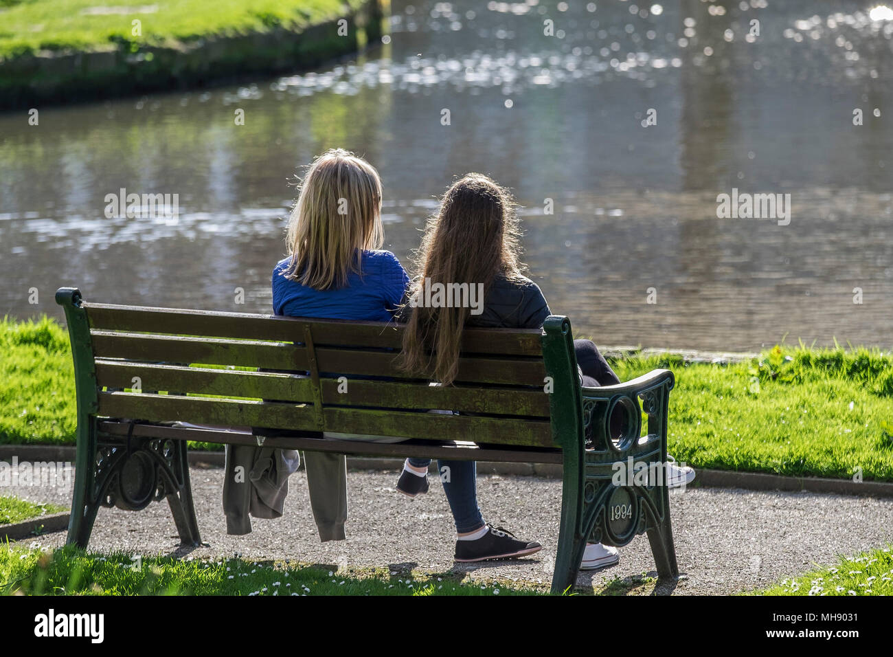 Zwei Freunde sitzen auf einer Bank mit Blick auf einen See. Stockfoto