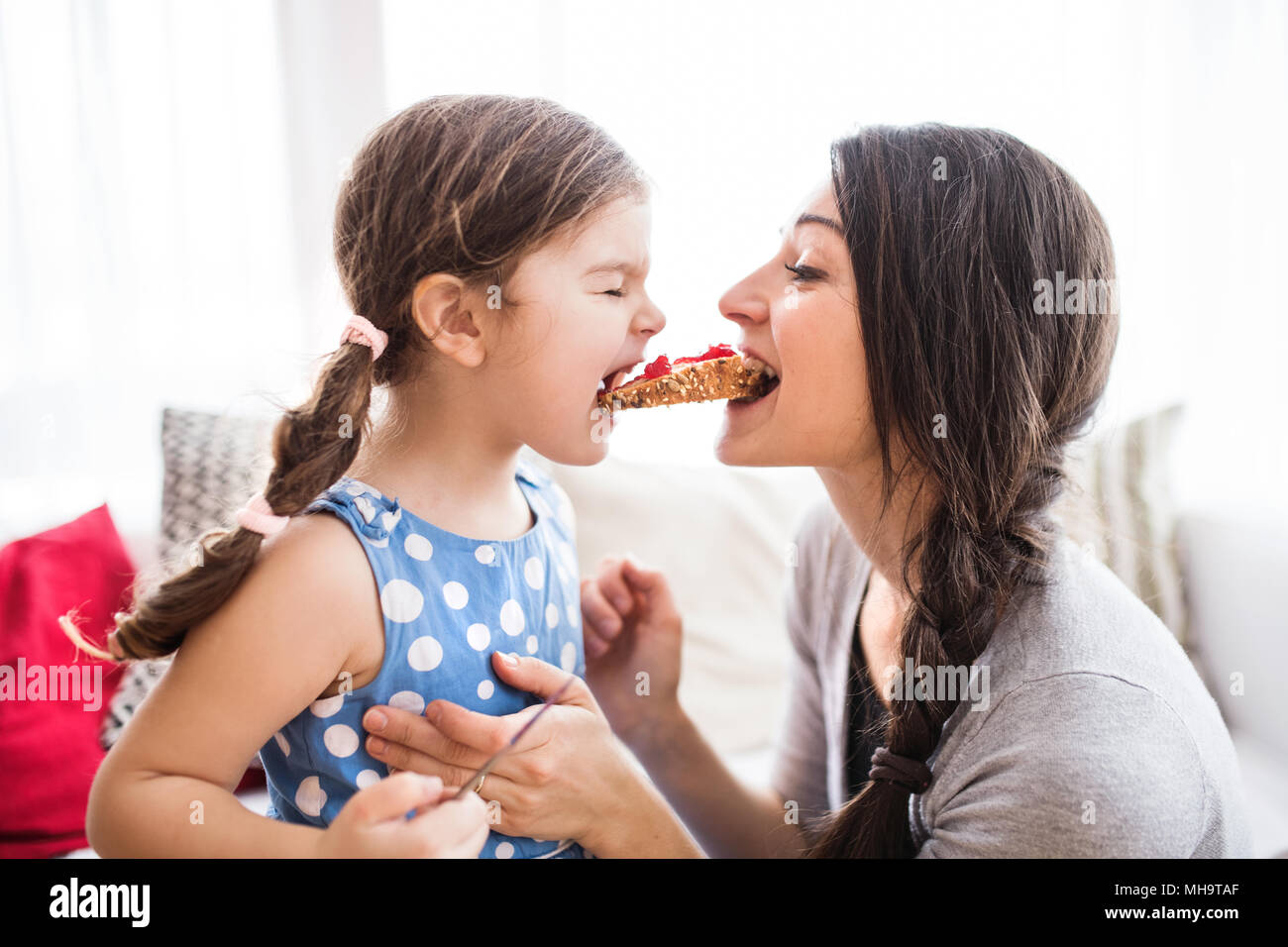 Junge Mutter mit einem kleinen Mädchen zu Hause, Essen. Stockfoto