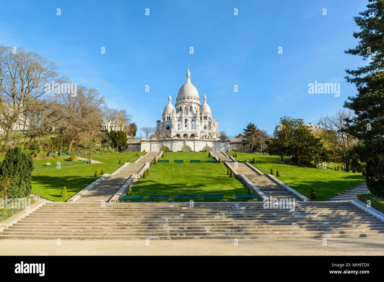 Vorderansicht der Basilika des Heiligen Herzen von Paris an der Spitze des Montmartre Hill von der Unterseite der Treppen in der Louise Michel Park. Stockfoto