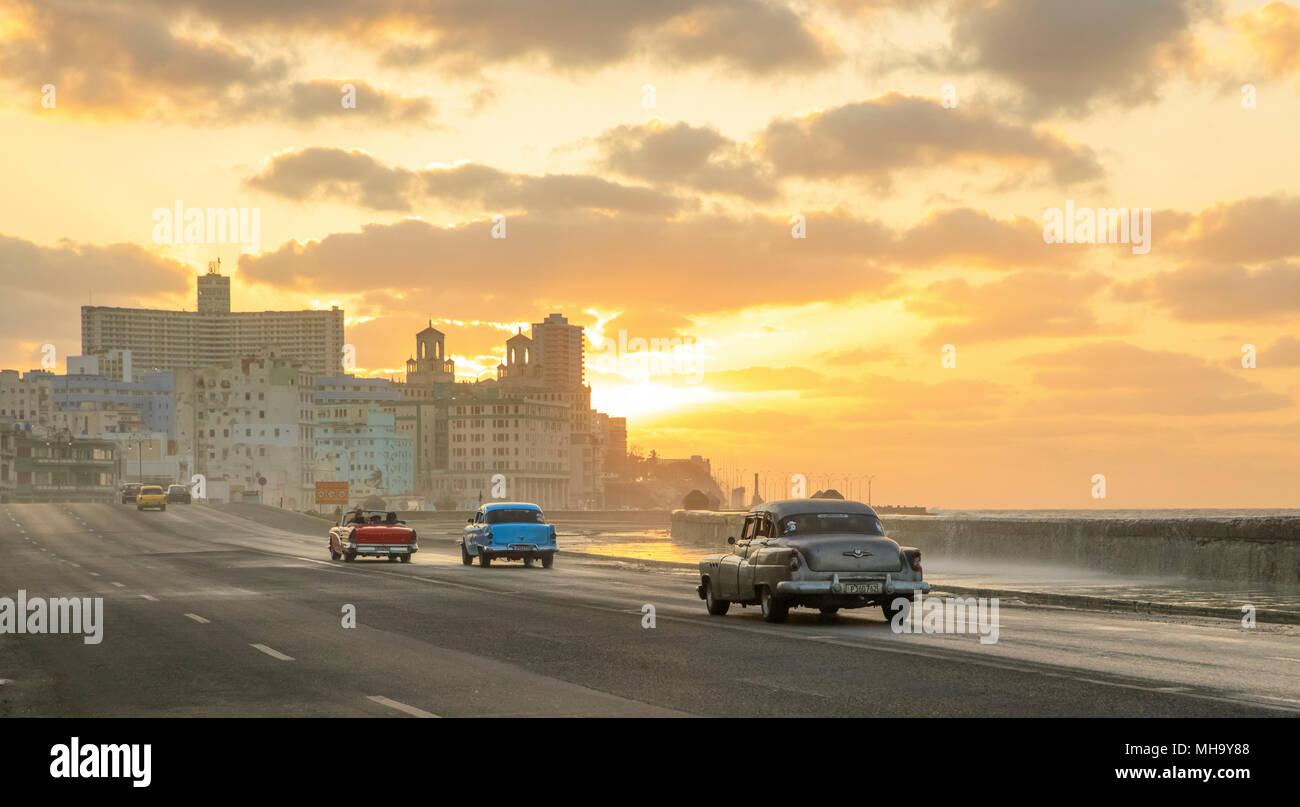 Wellen, wie die Sonne als klassische Autos entlang der Malecon in Havanna, Kuba reisen. Stockfoto