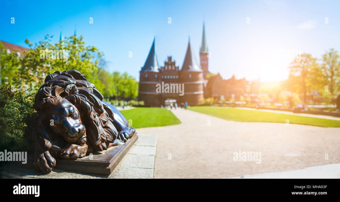 Bronze Lion Statue vor dem Holstentor - Panorama-aufnahme der Holstentor und Park, eine Stadt Tor markieren die westliche Grenze der Altstadt von Lübeck in Schleswig-Holstein Stockfoto