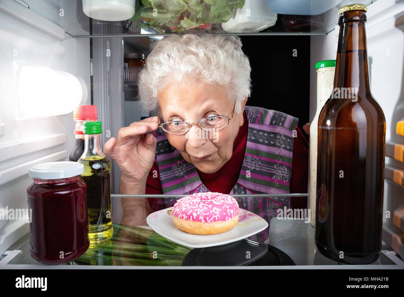 Oma entdecken ein Donut im Kühlschrank. Stockfoto