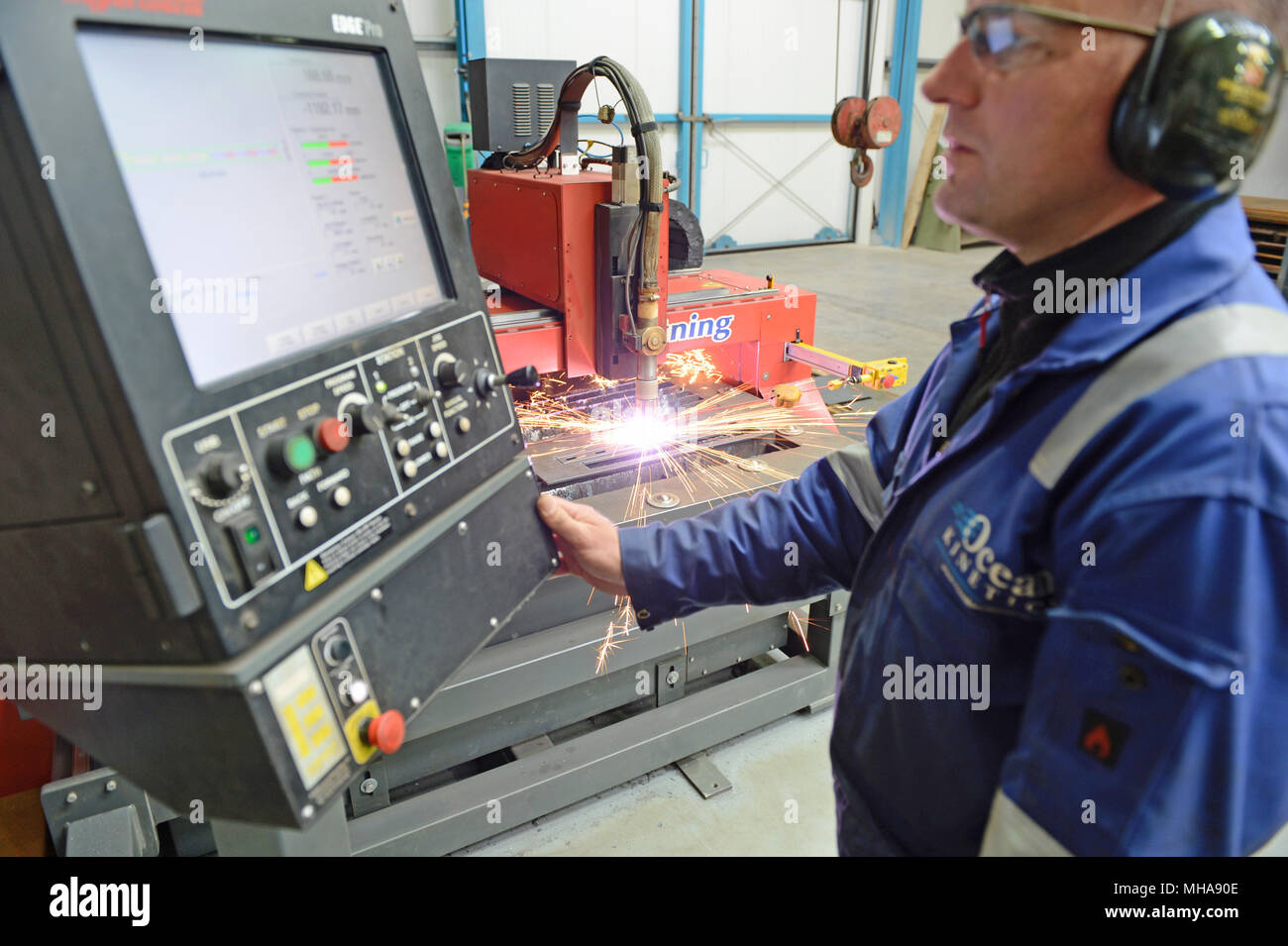 Mann bei der Arbeit auf einer metallenen Plasmaschneidemaschine in einer Werkstatt Stockfoto