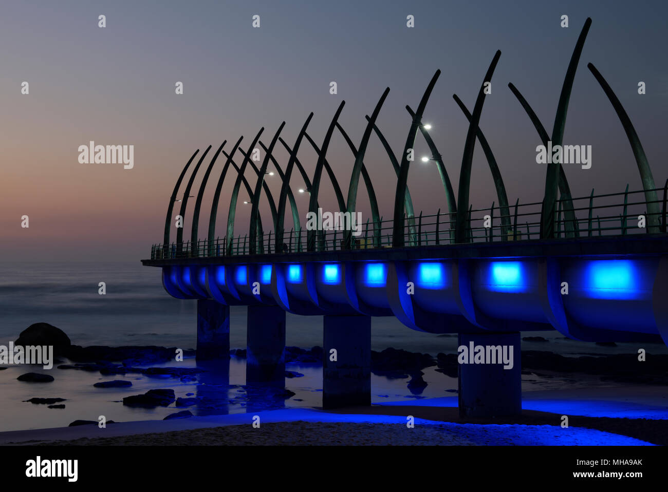 Durban, KwaZulu-Natal, Südafrika, Reihe der blauen Lichter auf Wahrzeichen Pier von Umhlanga Rocks Beach, Dämmerung, Landschaft Stockfoto