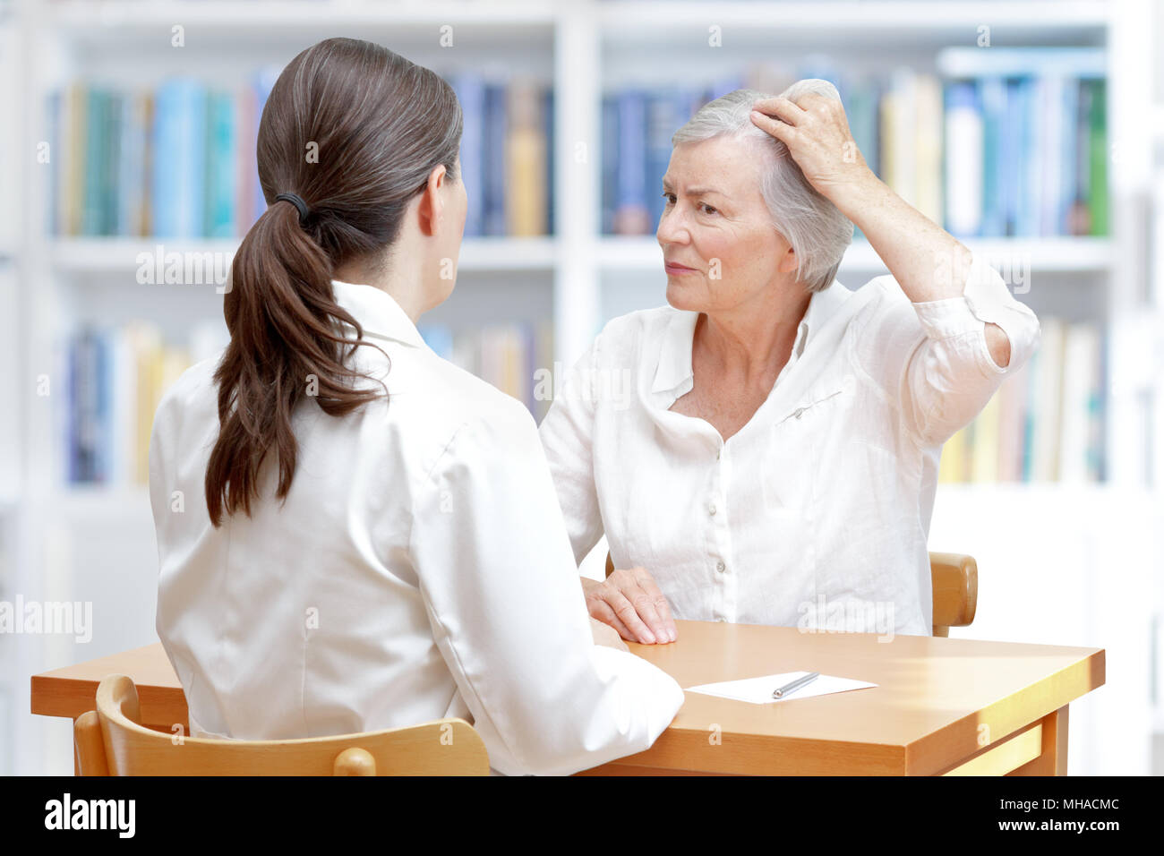 Ältere Frau mit grauen Haaren zeigen Ihr schütteres Haar oder Haarausfall zu Ihrer Ärztin Stockfoto