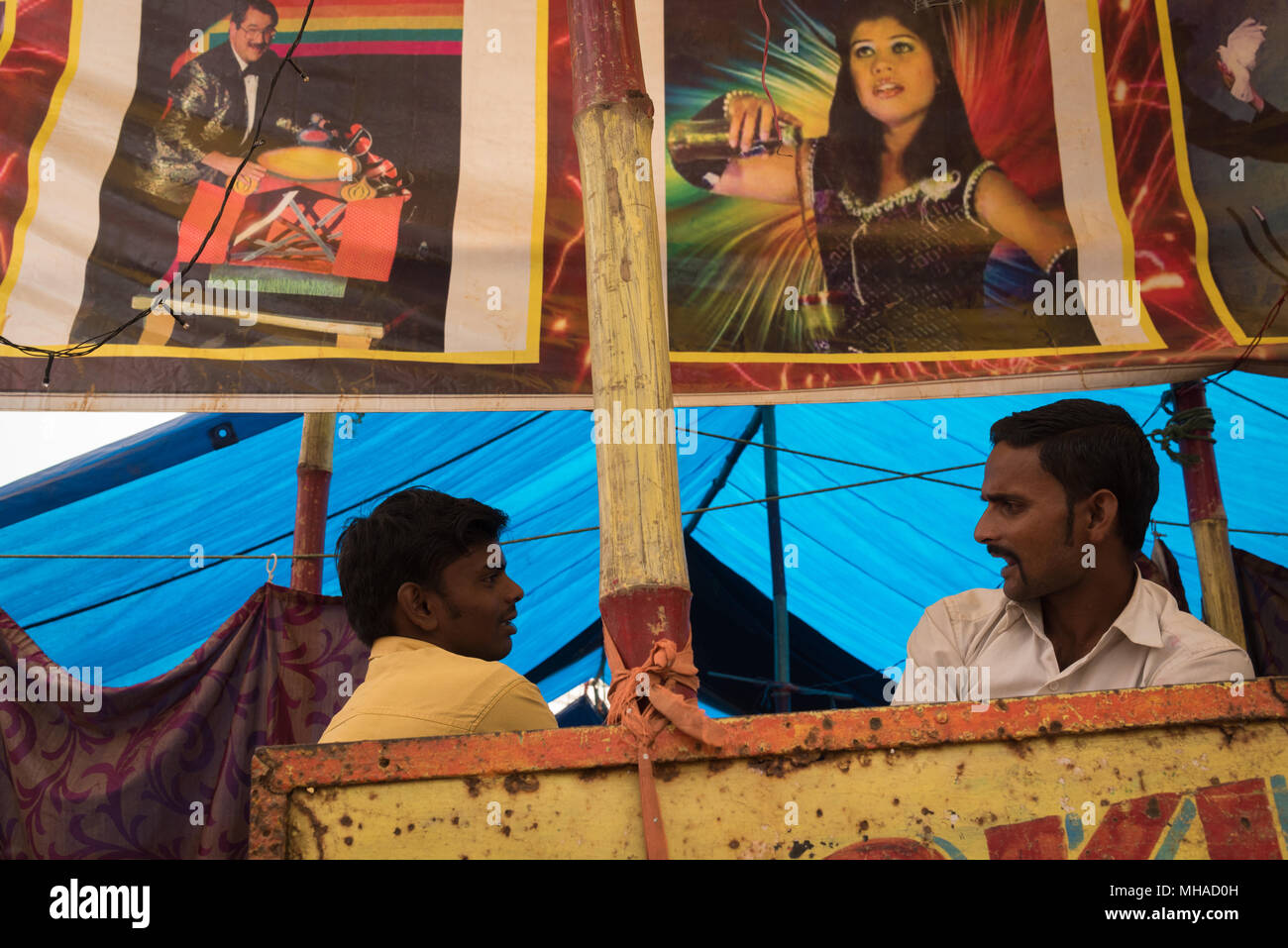 Zwei Männer im Gespräch unter Poster vor einem Zelt bis zur Unterhaltung am Sonepur Mela, Sonepur, Indien. Stockfoto