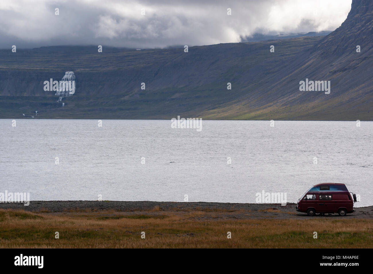 Touristische in seinem Volkswagen Westfalia Camper vor einem Wasserfall in den Westfjorden Region, Island Stockfoto