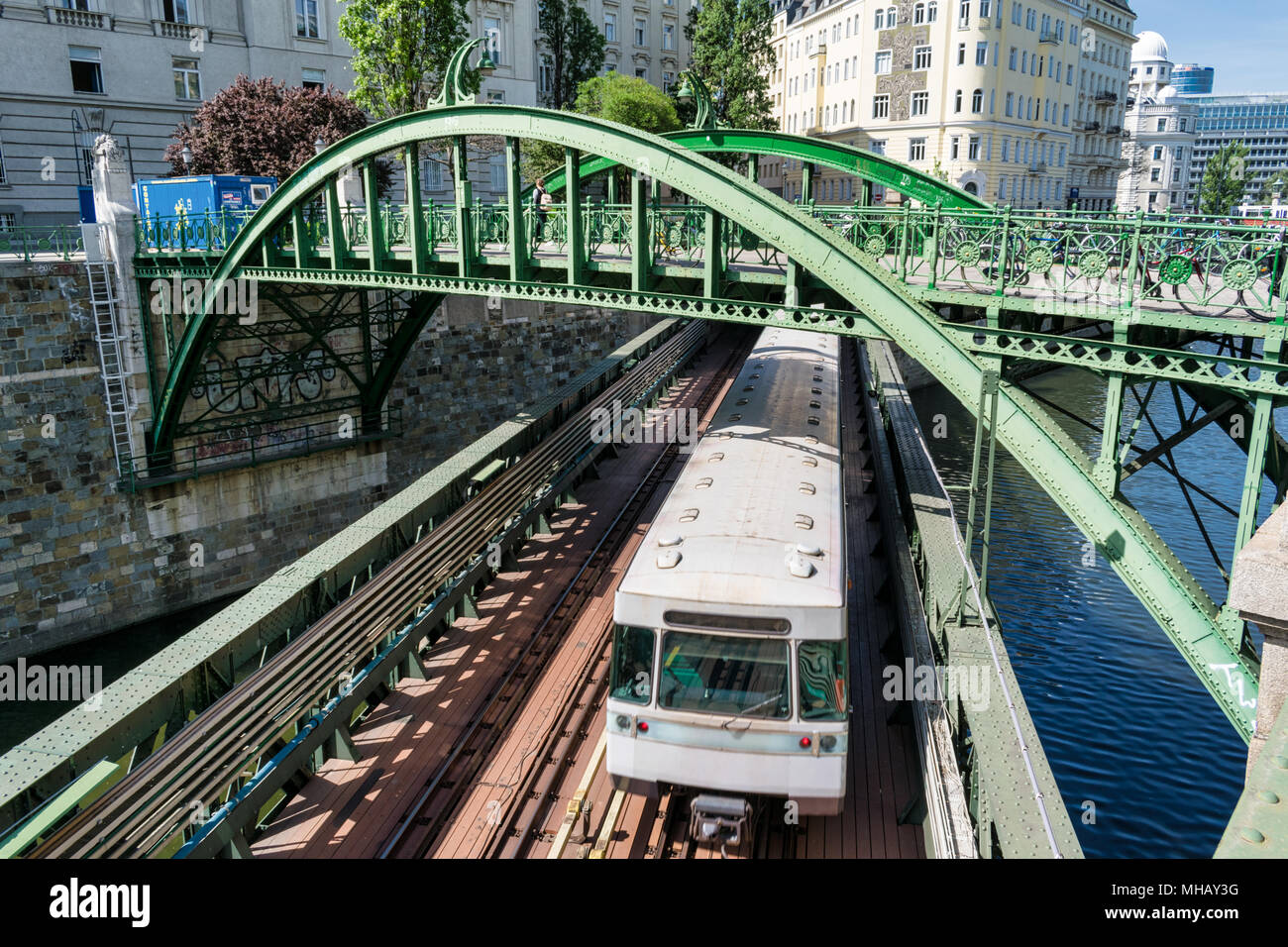 Dies ist ein Foto von einer U-Bahn, die einen Fluß überquert, in Wien über eine Brücke, während gleichzeitig unter einer anderen Brücke gehen. Stockfoto
