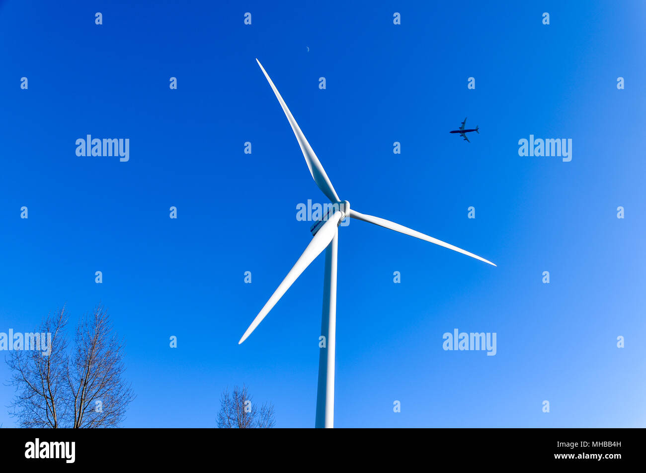 Ebene hinter einer Windenergieanlage auf einem blauen Himmel Hintergrund fliegen Stockfoto