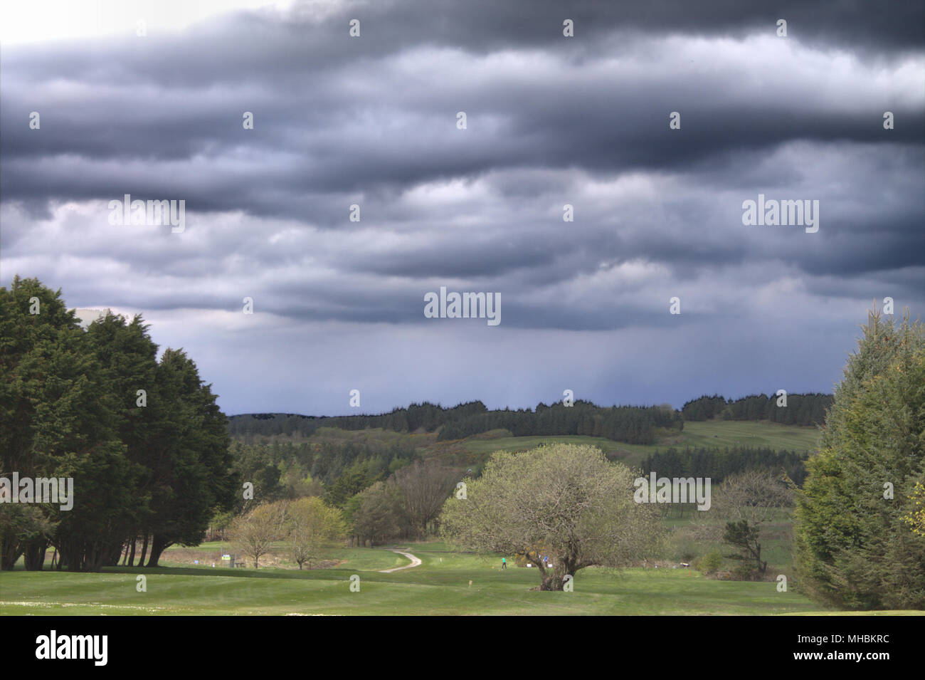 Gewitter wolken über Spieler, die auf einem Golfplatz. Stockfoto