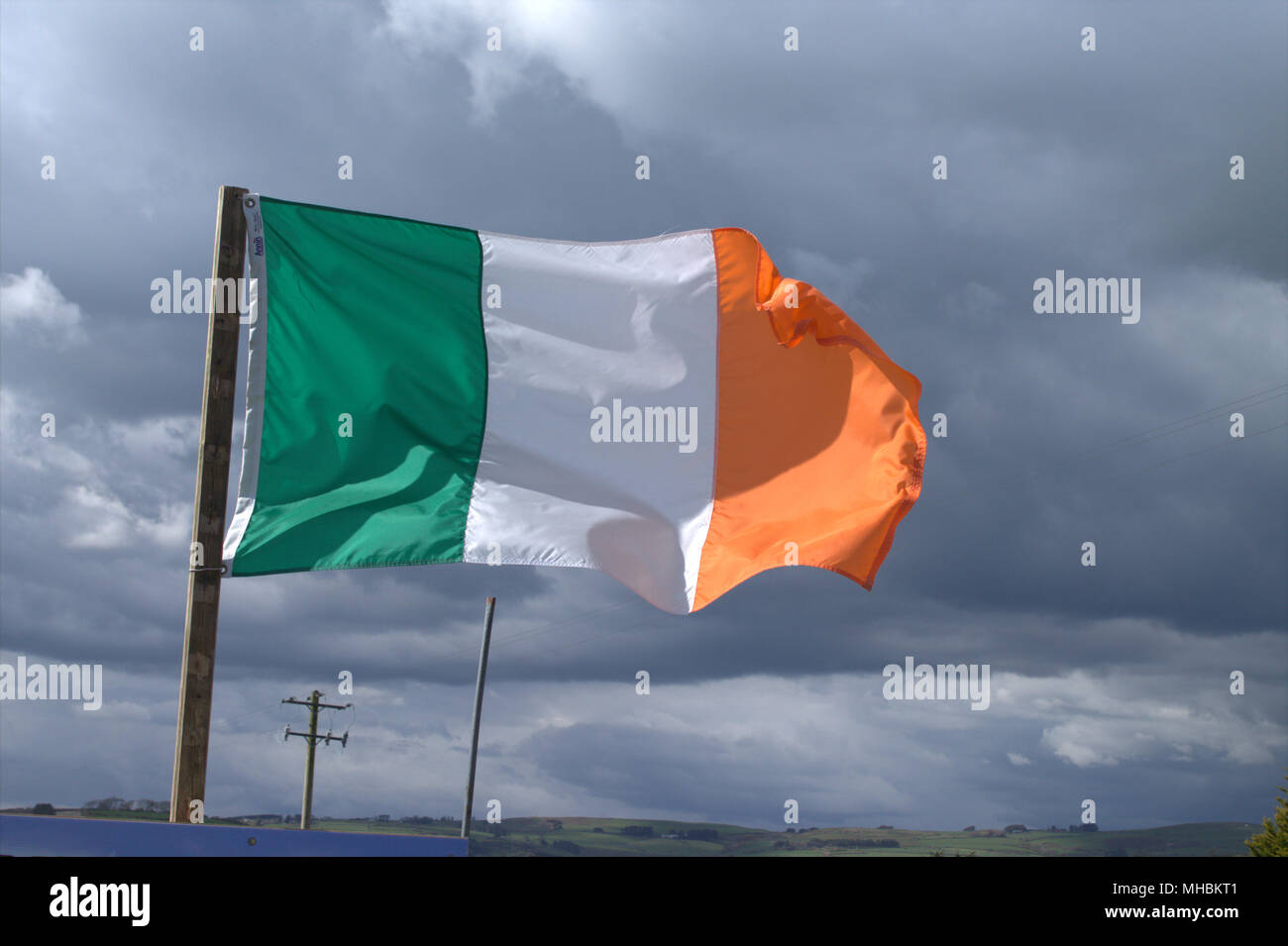 Irland Nationalflagge Tricolour und Stern der Republik Irland fliegen in einem steifen Wind gegen einen stürmischen Himmel. Stockfoto