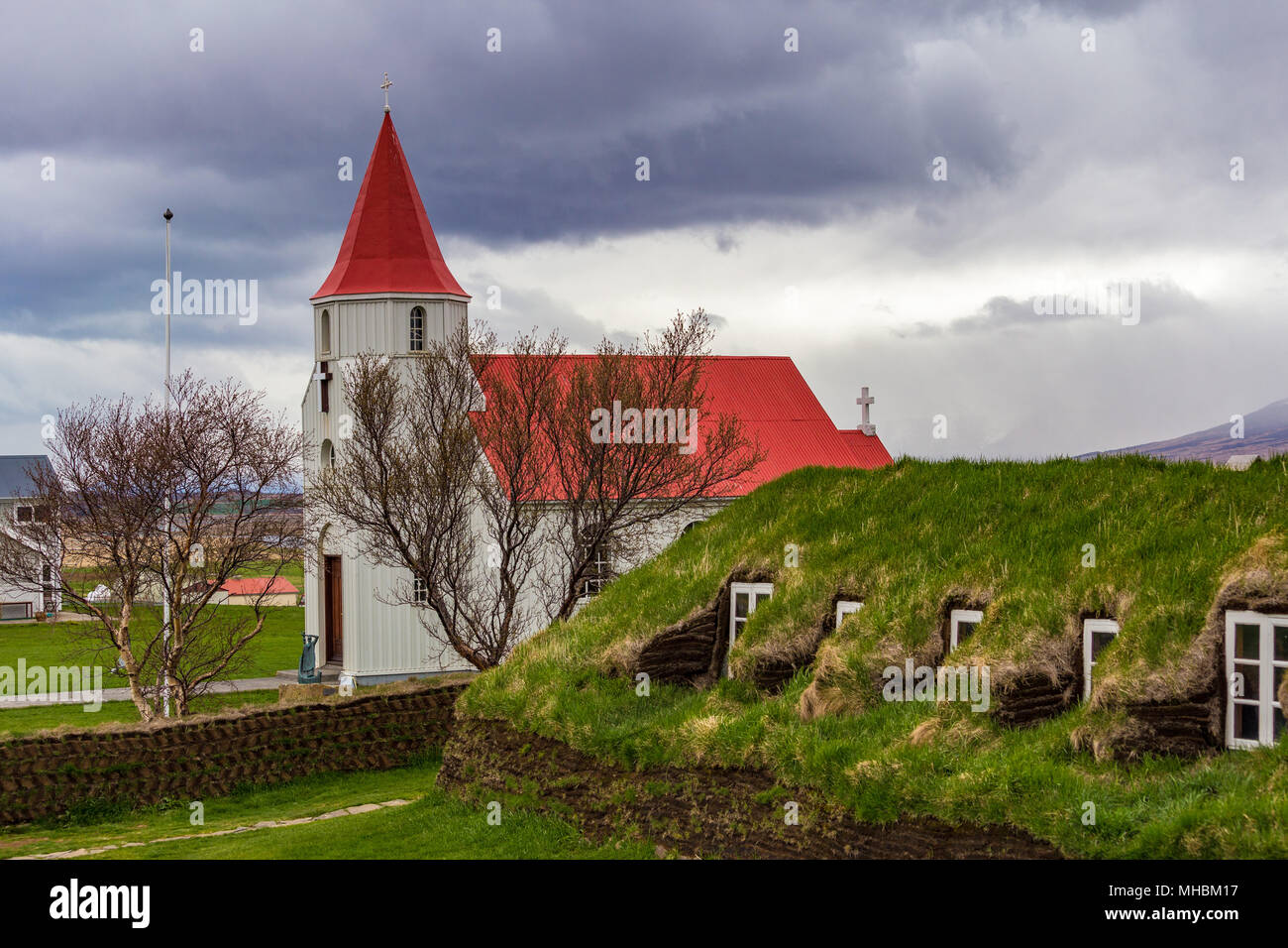 Rote überdachte Kirche in Glaumbaer Dorf und kleine Hütten mit Rasen Dächer im Norden Island Stockfoto