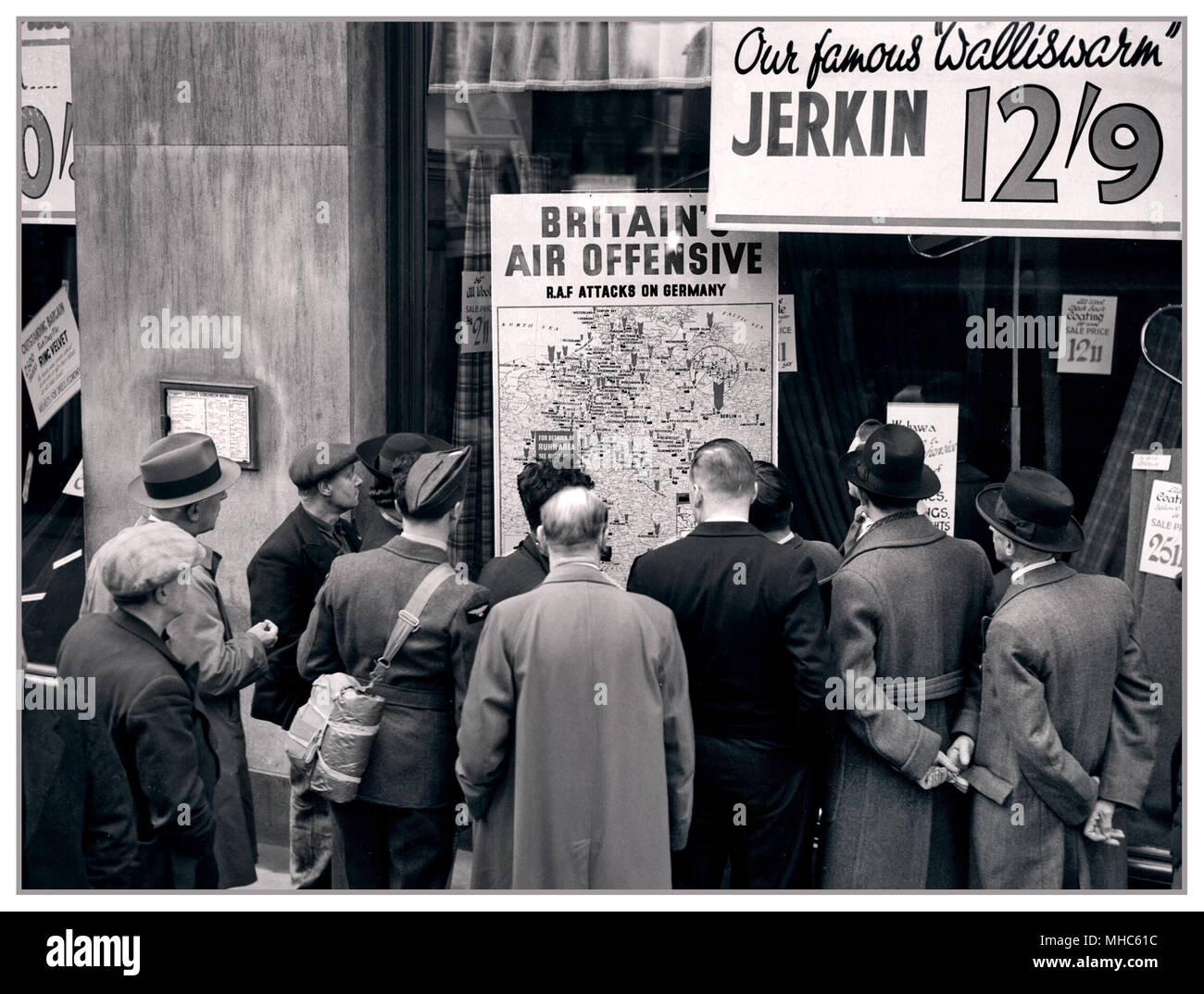 Ein britischer Flieger gehört zu einer Gruppe von Zivilisten rund um das Fenster von einem Shop in Holborn, London überfüllt, auf eine Landkarte, die veranschaulicht, wie die RAF in Deutschland Auffällig ist bei 1940 zu suchen Stockfoto