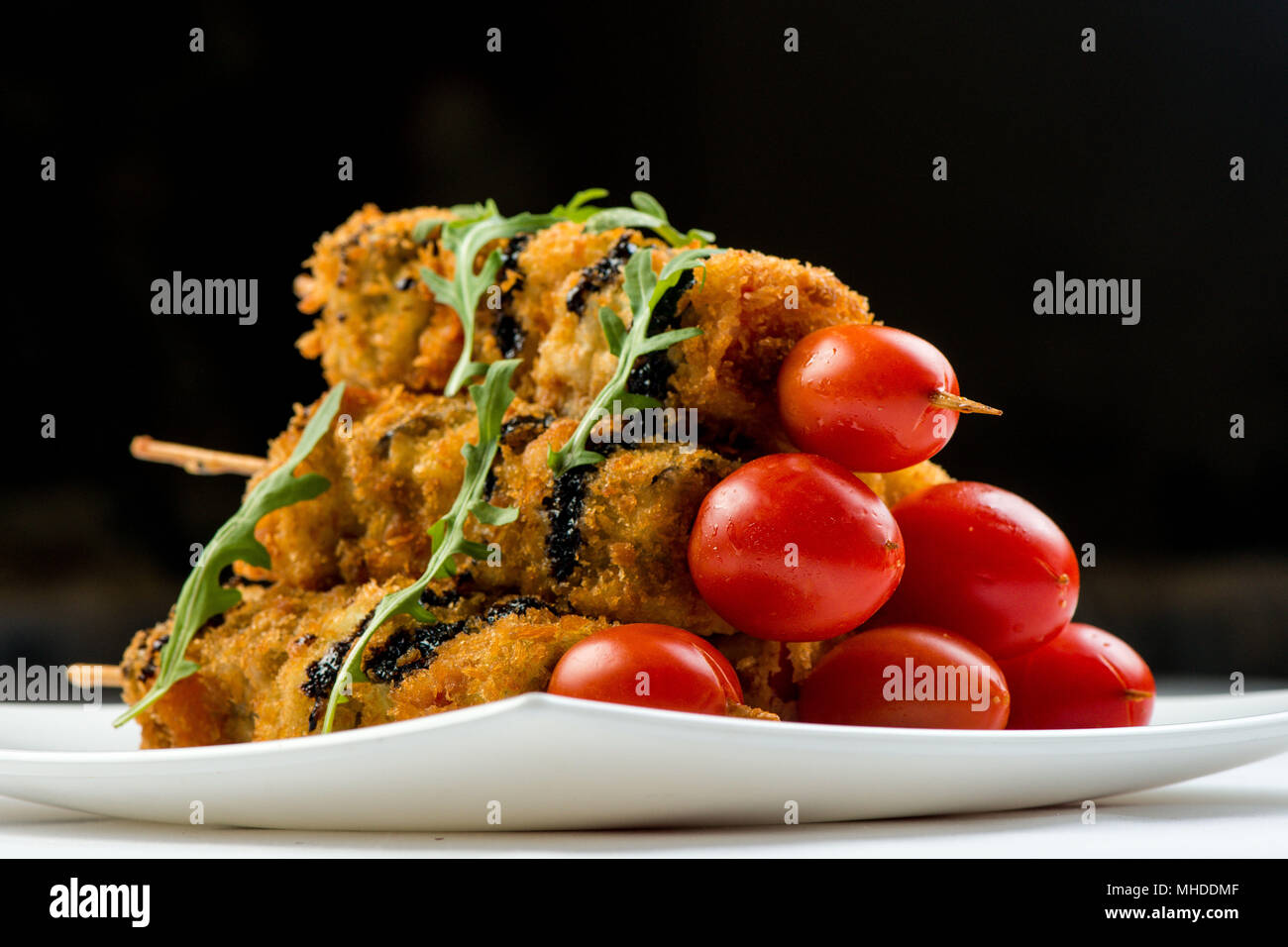 Gemüse am Spieß gebraten in Teig dekoriert mit Tomaten, Zucchini, Auberginen, Zucchini. weiße Platte auf weißem Hintergrund Stockfoto