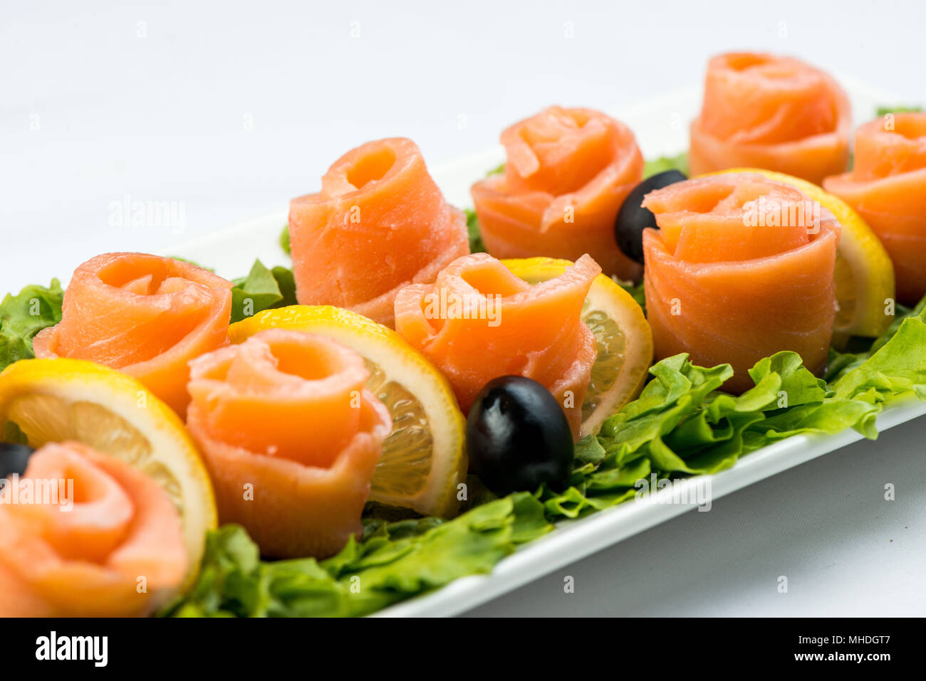 Lachs Snack auf Salatblatt mit Zitronen und Oliven auf weiße Platte auf weißem Hintergrund Stockfoto