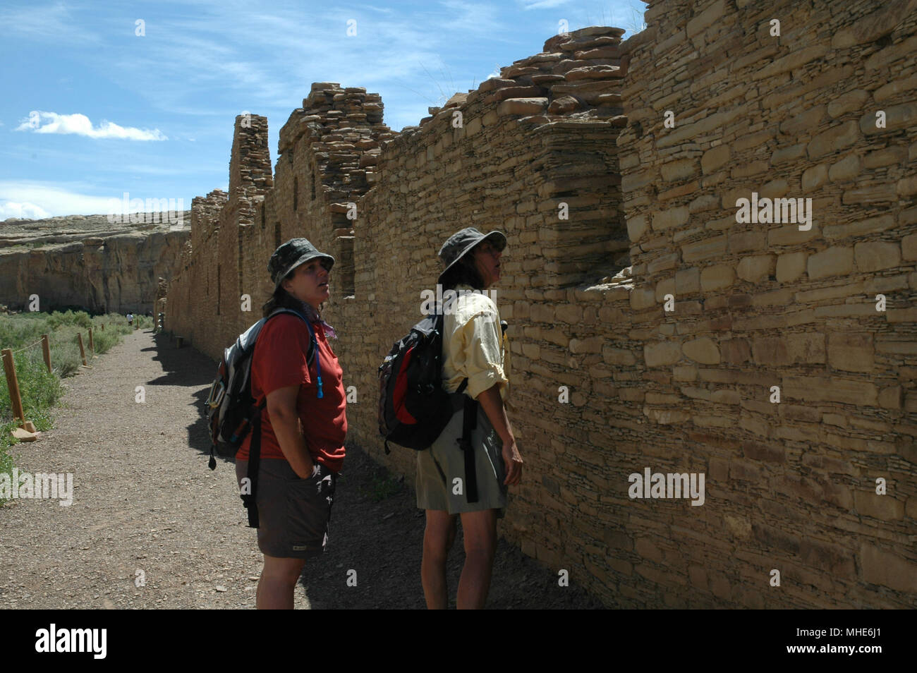 Ein paar Touristen schauen Sie über eine zerstörte Wand eines alten Pueblo im Chaco Canyon. Stockfoto