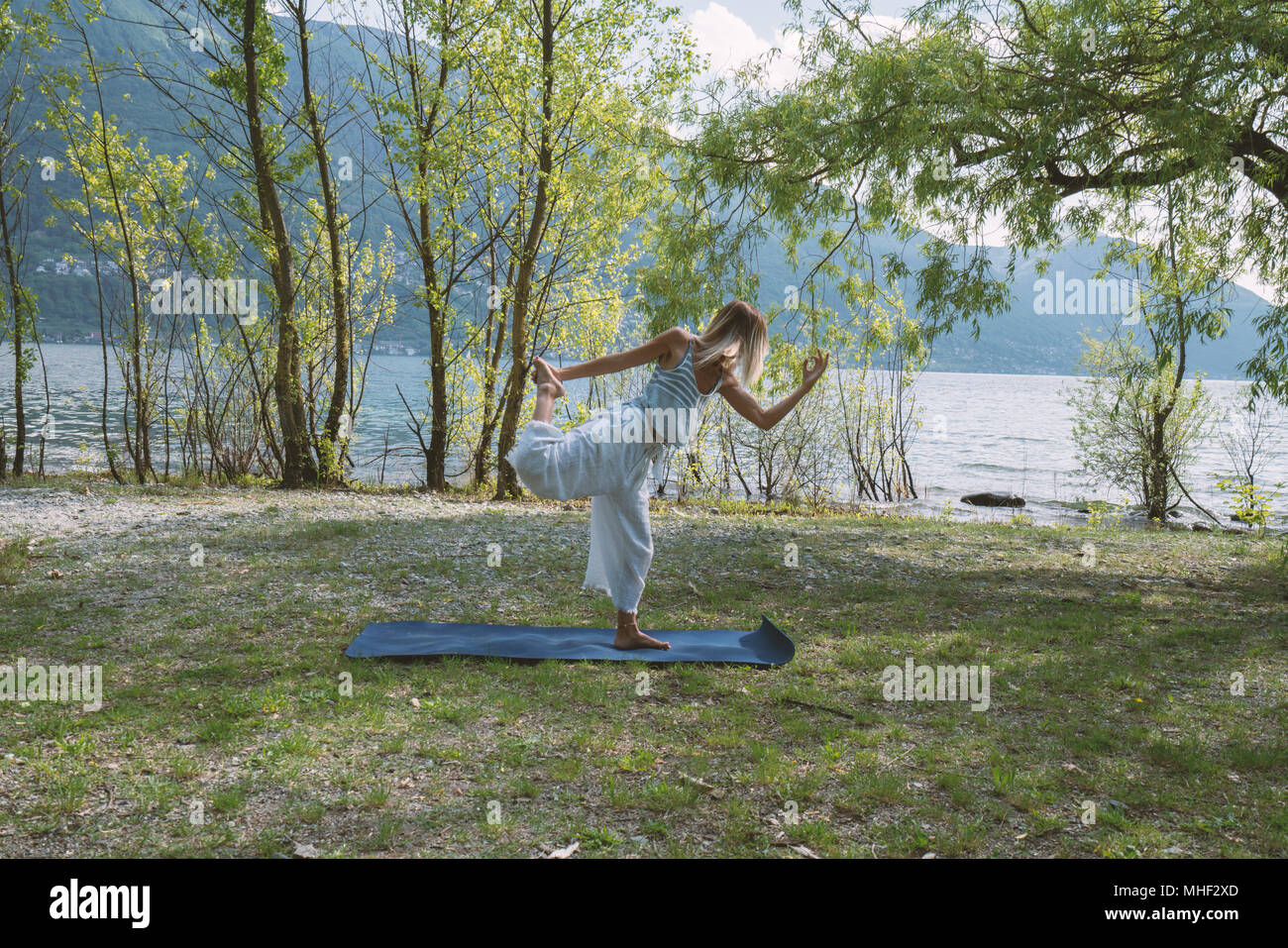 Junge Frau trainieren Yoga durch den See und die Berge, im Kanton Tessin, Schweiz, Europa erschossen. Menschen Entspannung Wohlbefinden Konzept Stockfoto