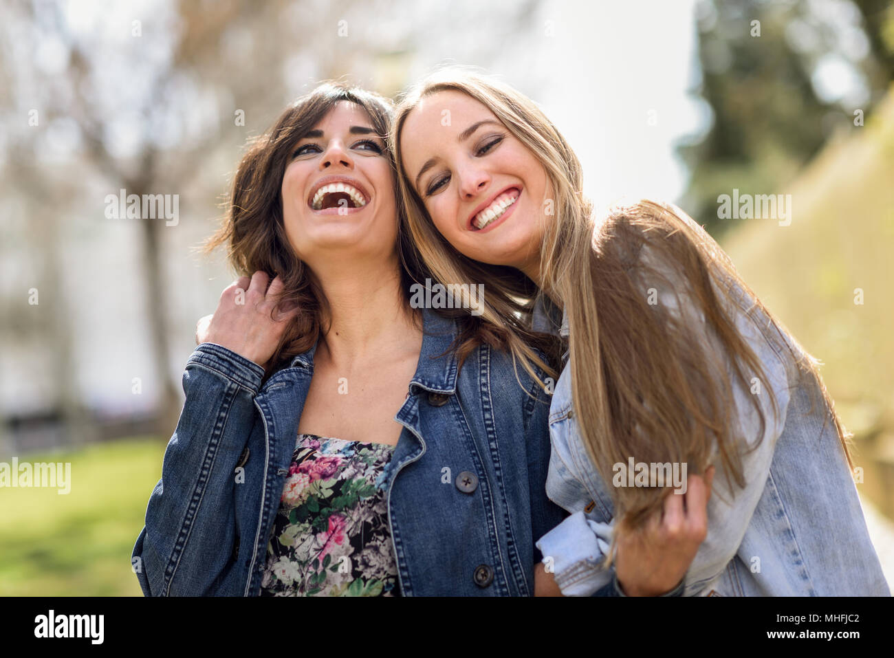 Zwei glückliche junge Frauen Freunde umarmen in der Straße. Blonde und brünette Mädchen legere Kleidung im Freien. Stockfoto